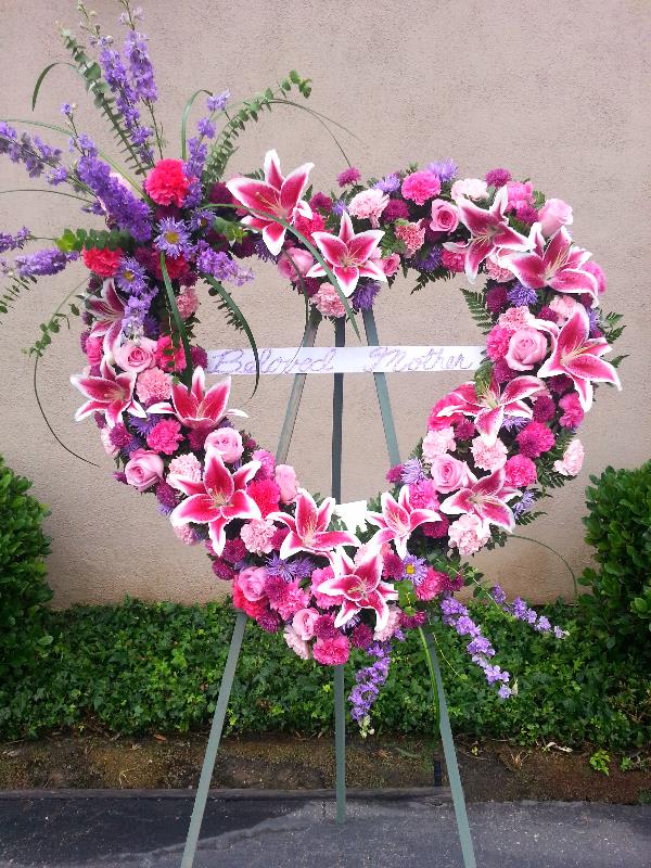 Heart-shaped floral wreath on an easel with pink and purple flowers
