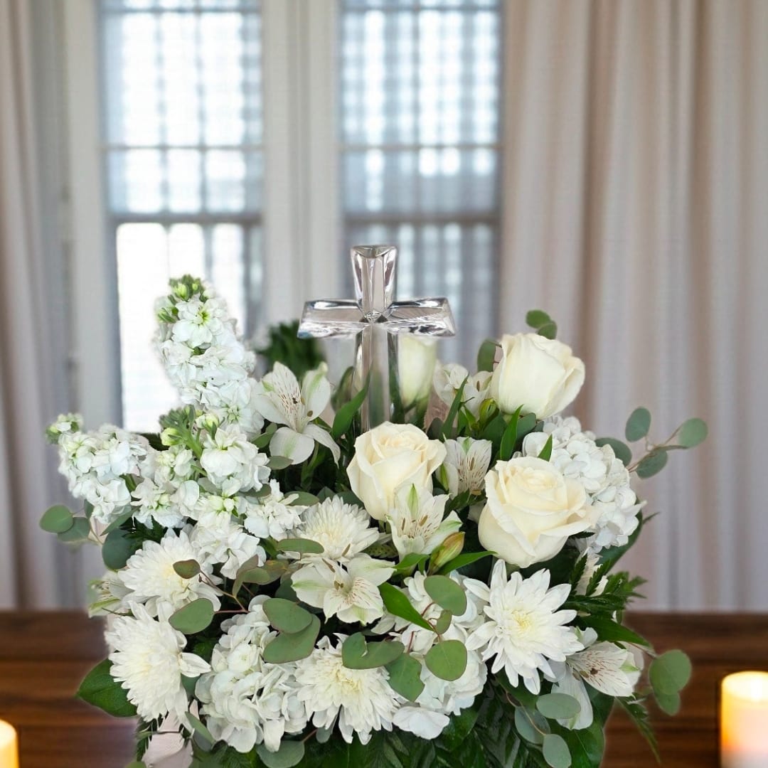White floral arrangement with roses and a clear cross centerpiece