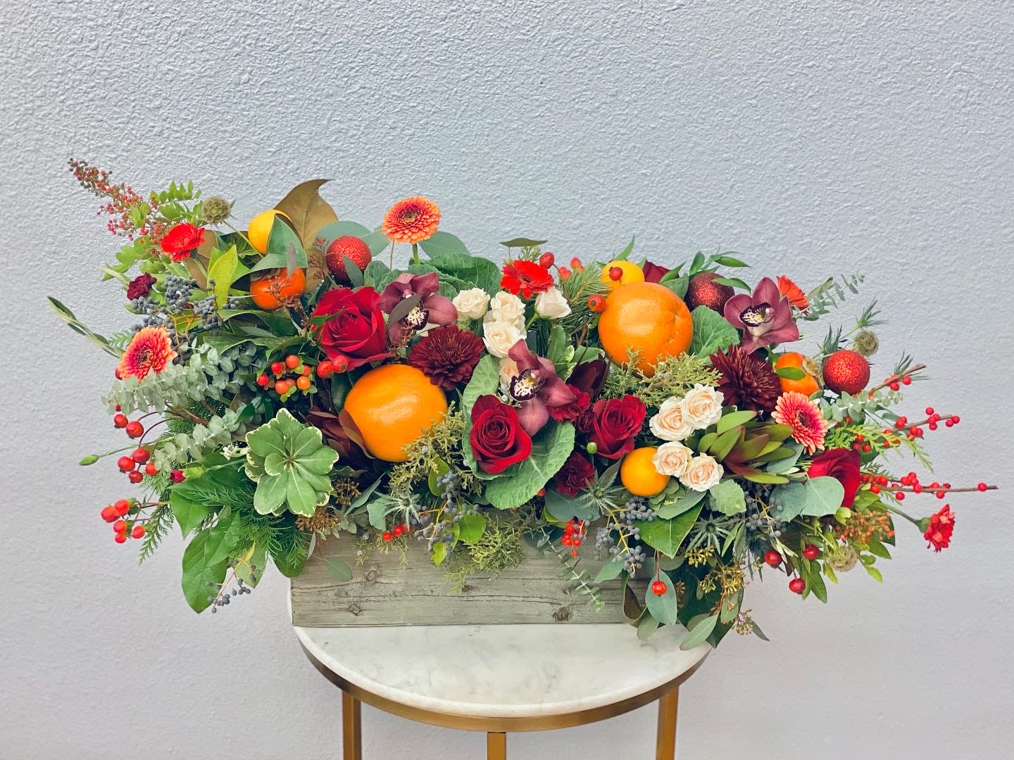 Mixed floral arrangement with oranges in a wooden box