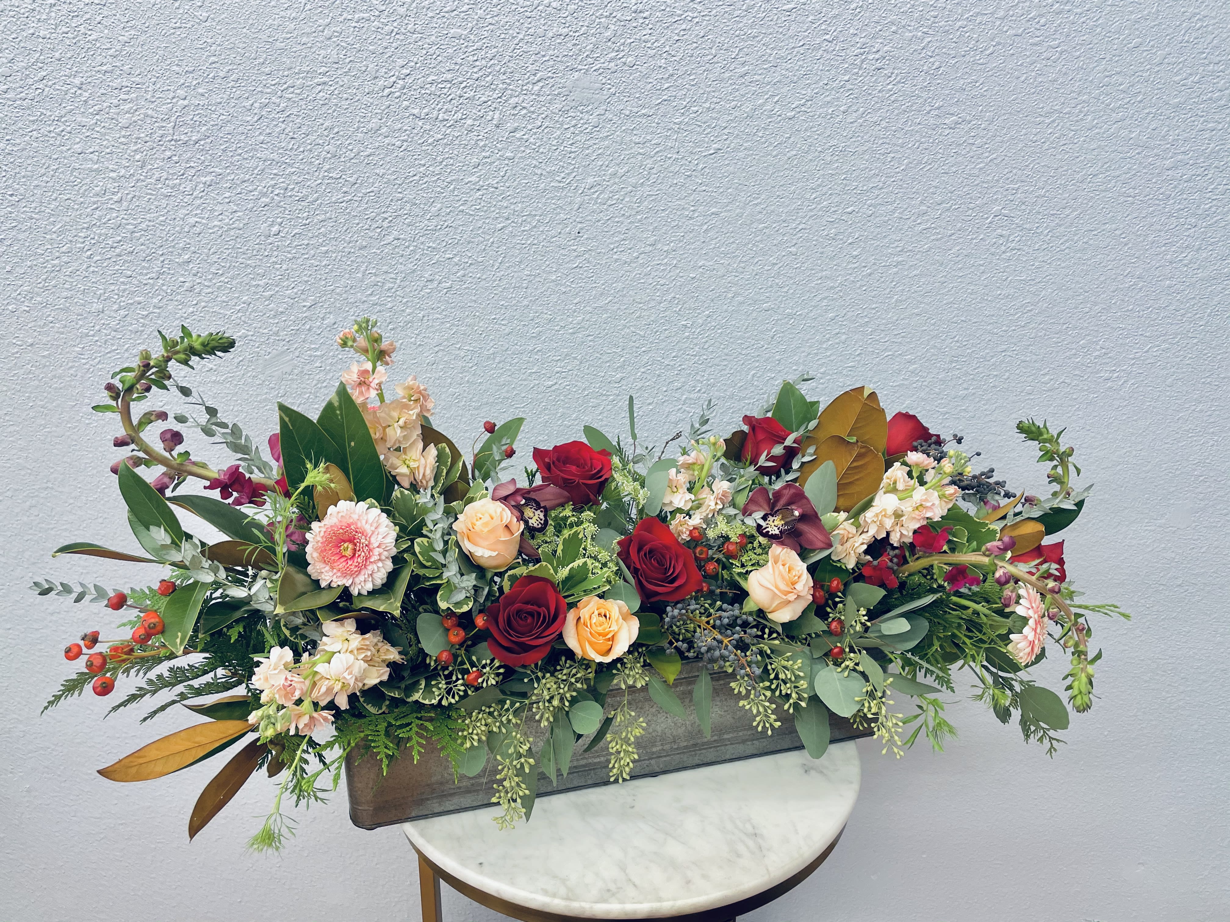 Long floral centerpiece with red and peach roses in a rectangular container