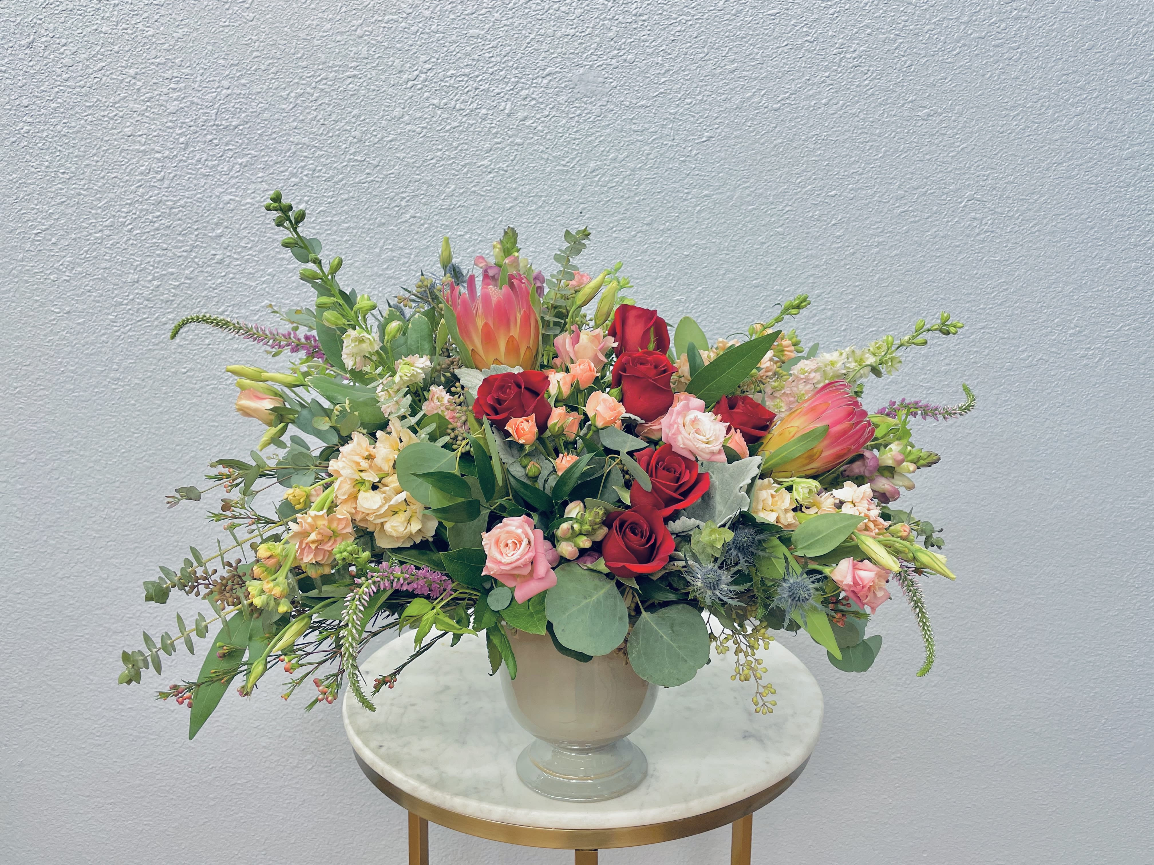 Mixed bouquet of red and pink roses with tropical blooms in a vase