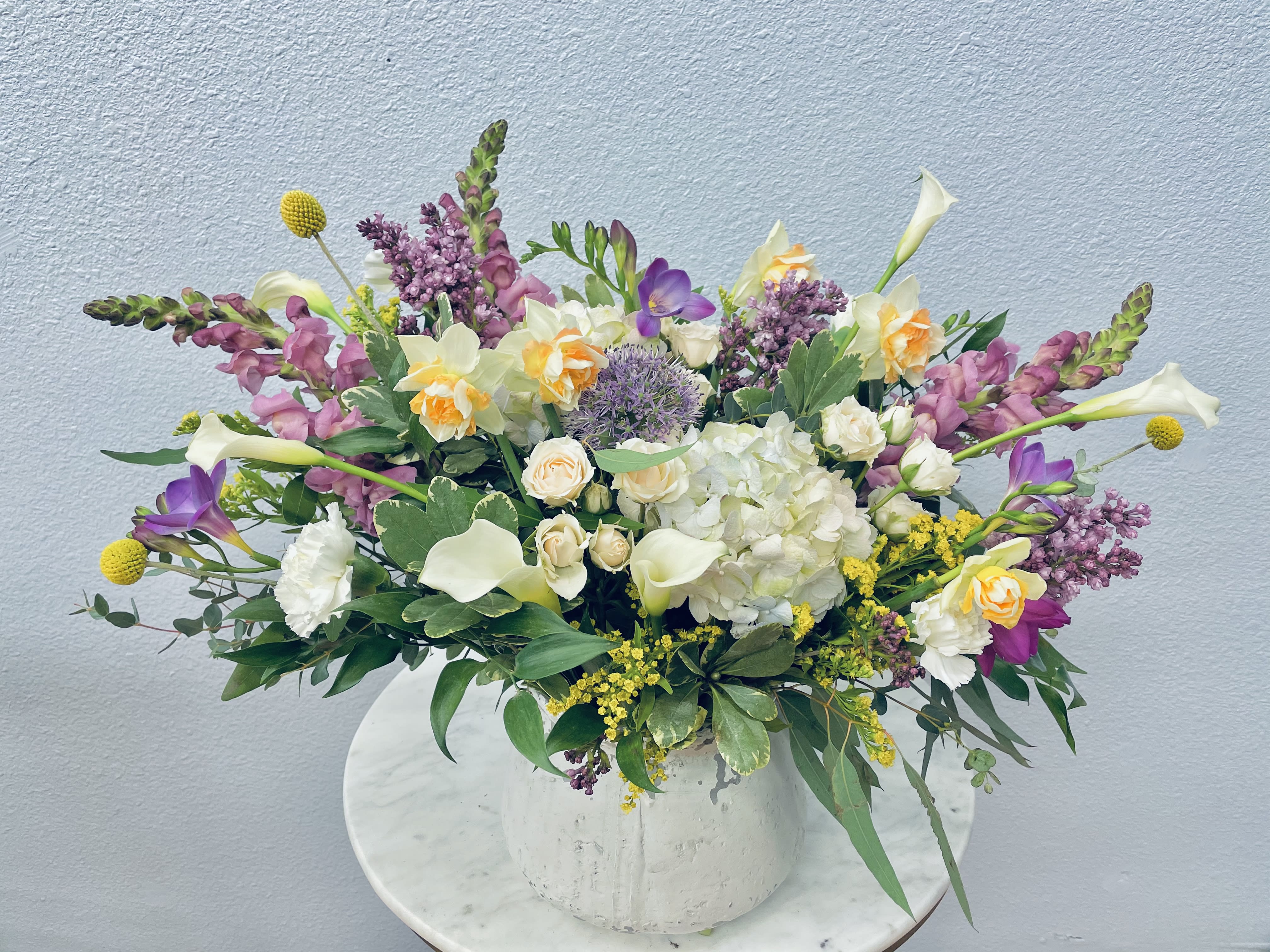 Mixed bouquet in a white vase with white, purple, and yellow flowers