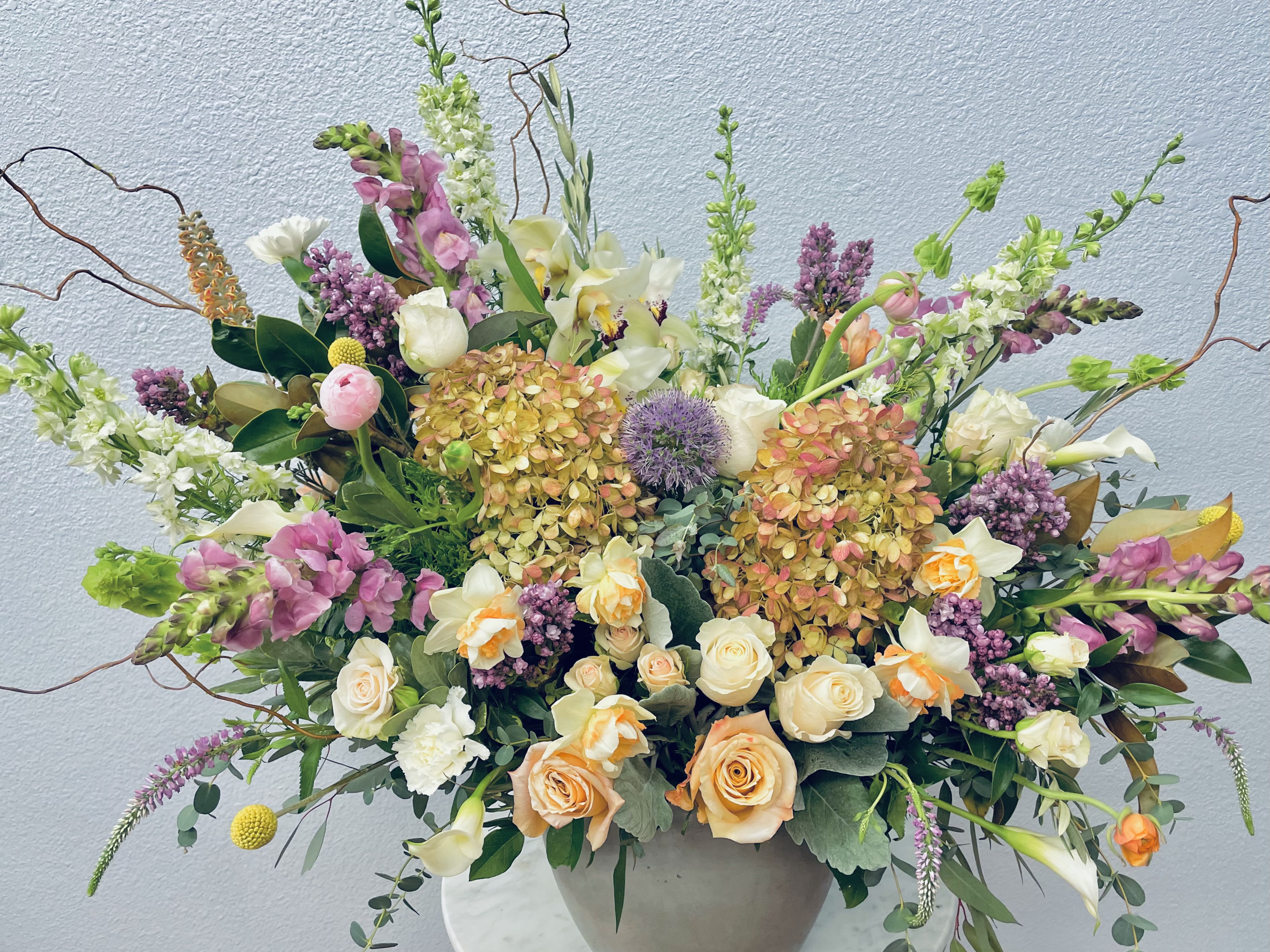 Large mixed floral arrangement in a round vase with pink, white, and peach blooms