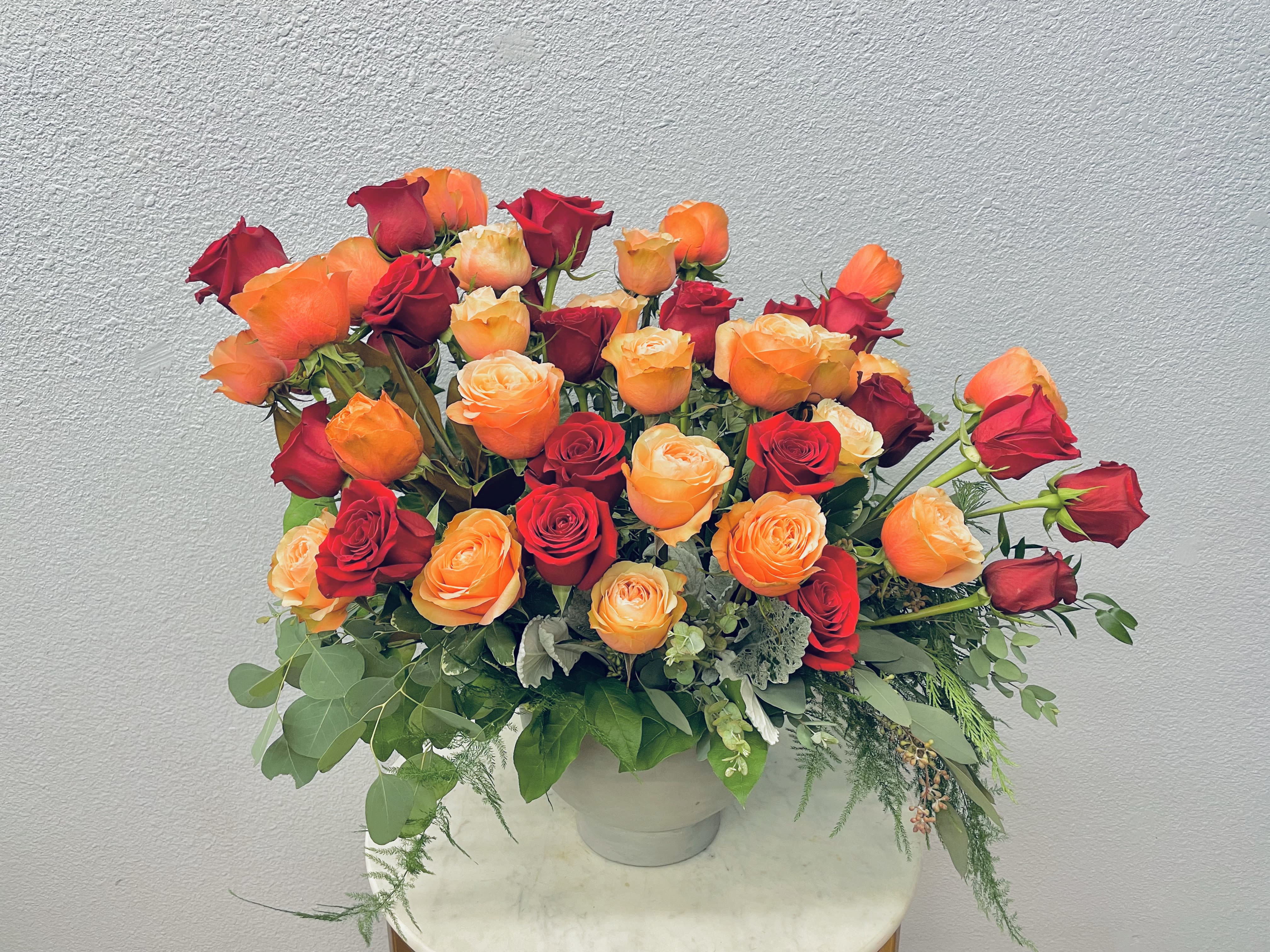 Bouquet of red and orange roses in a white vase