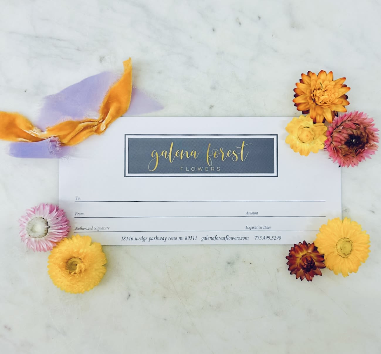 Gift card surrounded by colorful dried flowers and ribbon