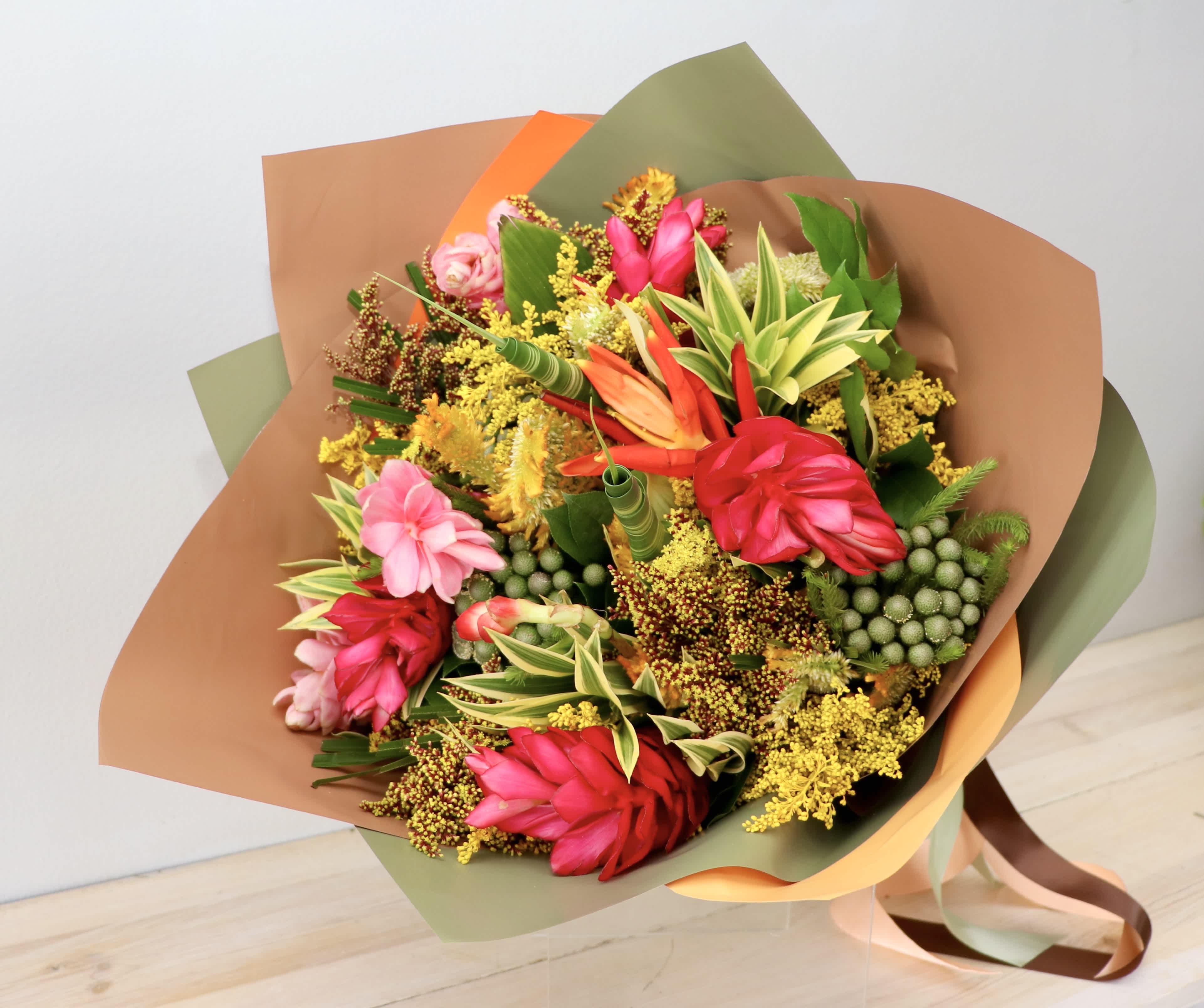 Bouquet of bright tropical flowers wrapped in brown and green paper