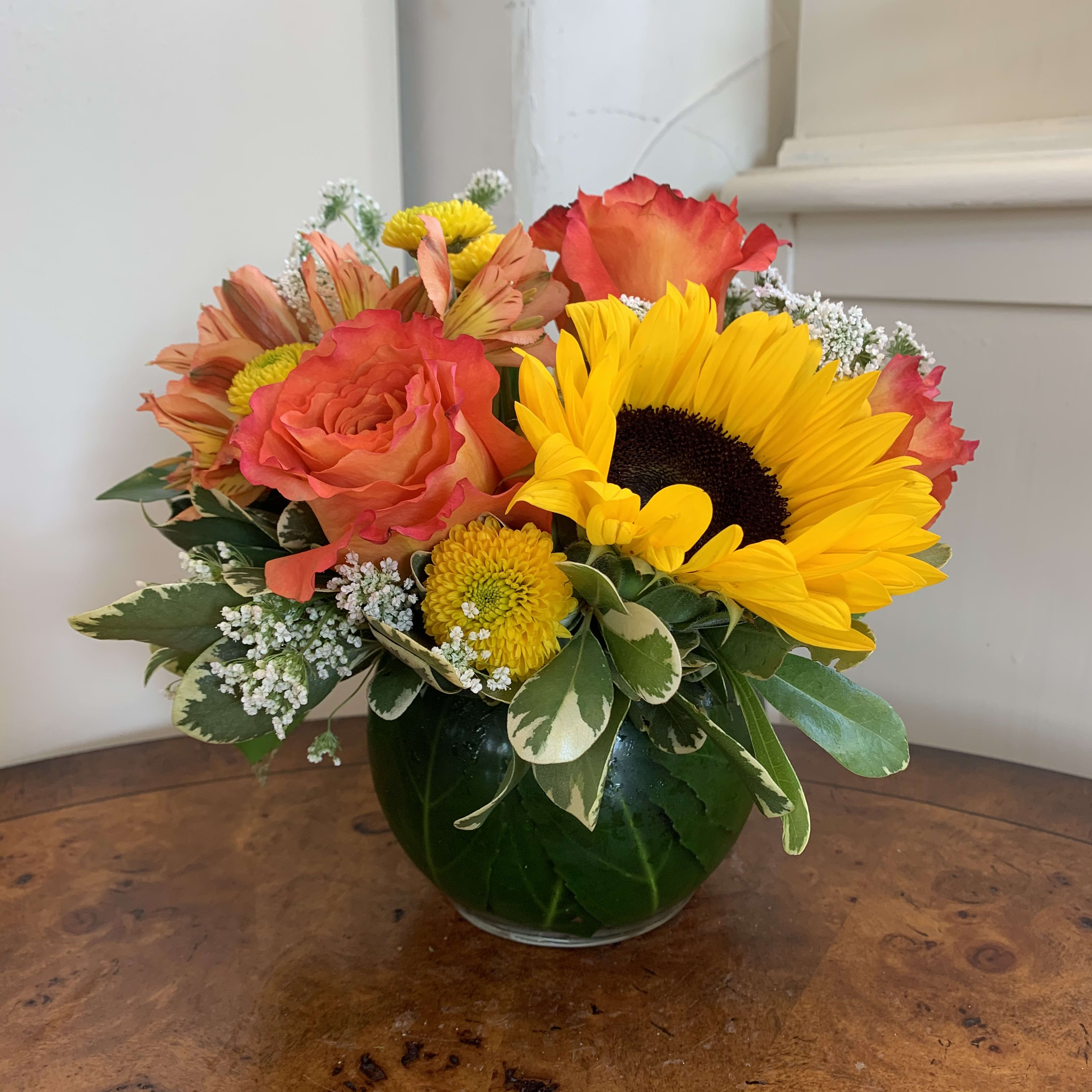 Bouquet of sunflowers, roses, and mixed blooms in a glass vase