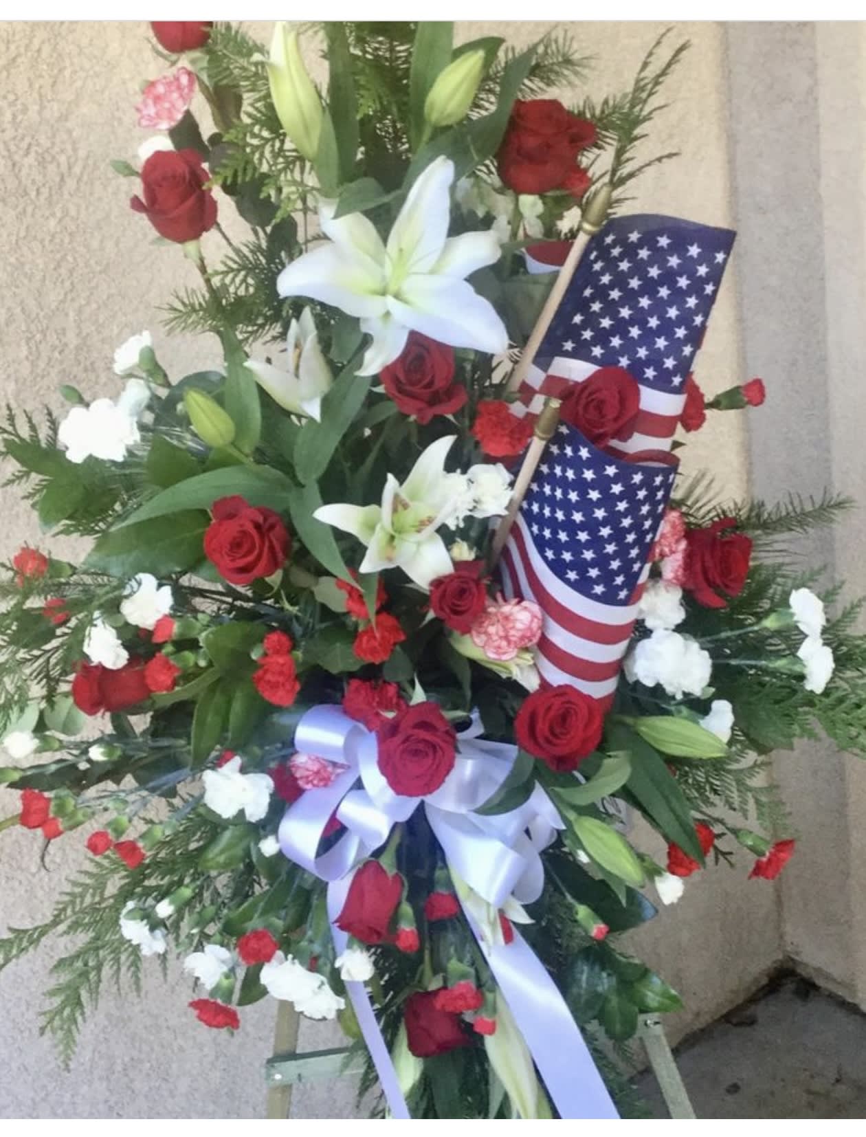 Standing floral spray with red roses, white lilies, and American flags