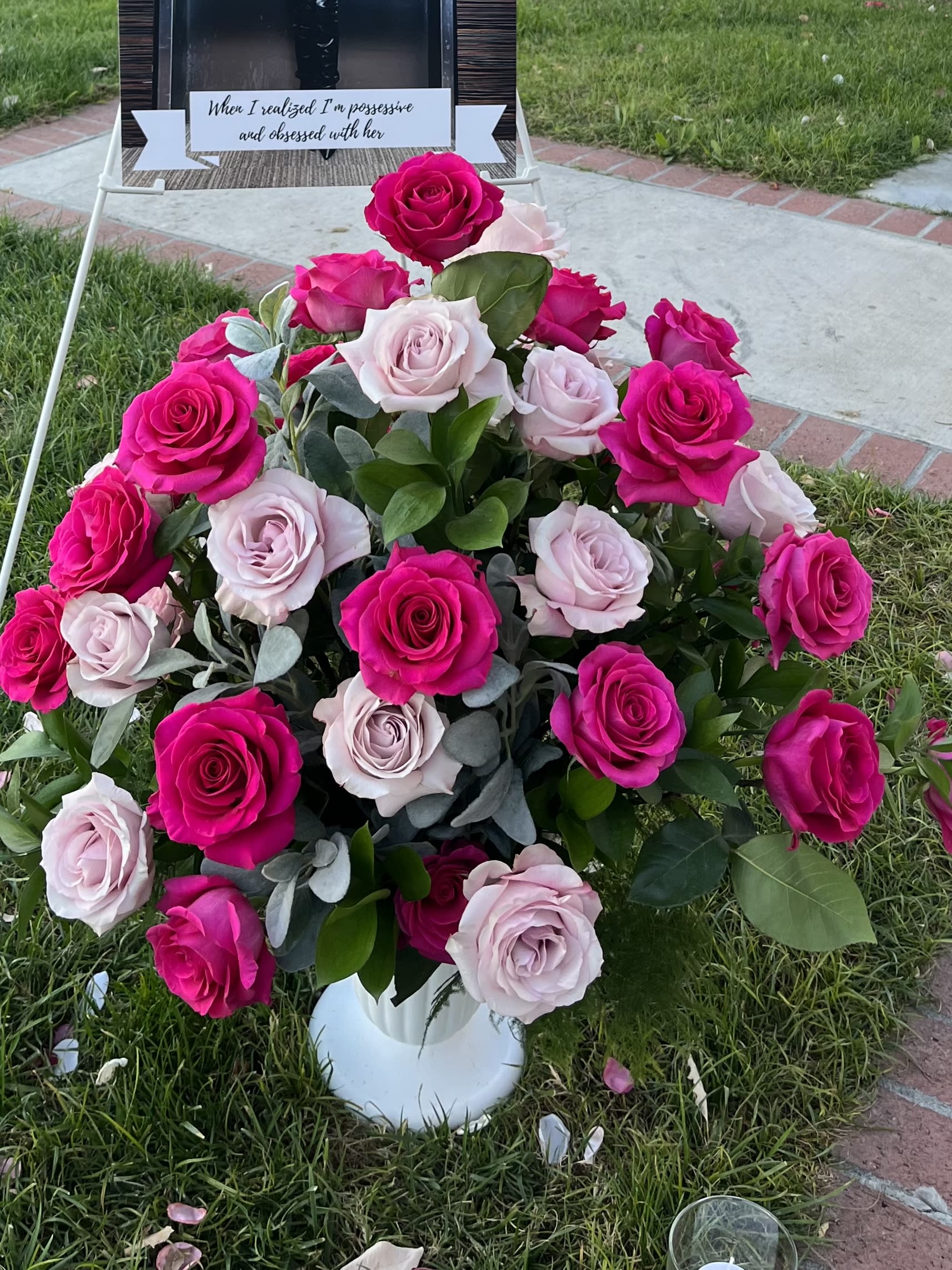 Pink and pale roses arranged in a white vase outdoors
