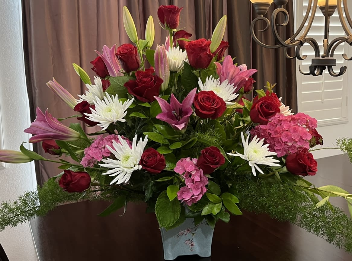 Bouquet of red roses, pink lilies, white daisies, and pink hydrangeas in a vase