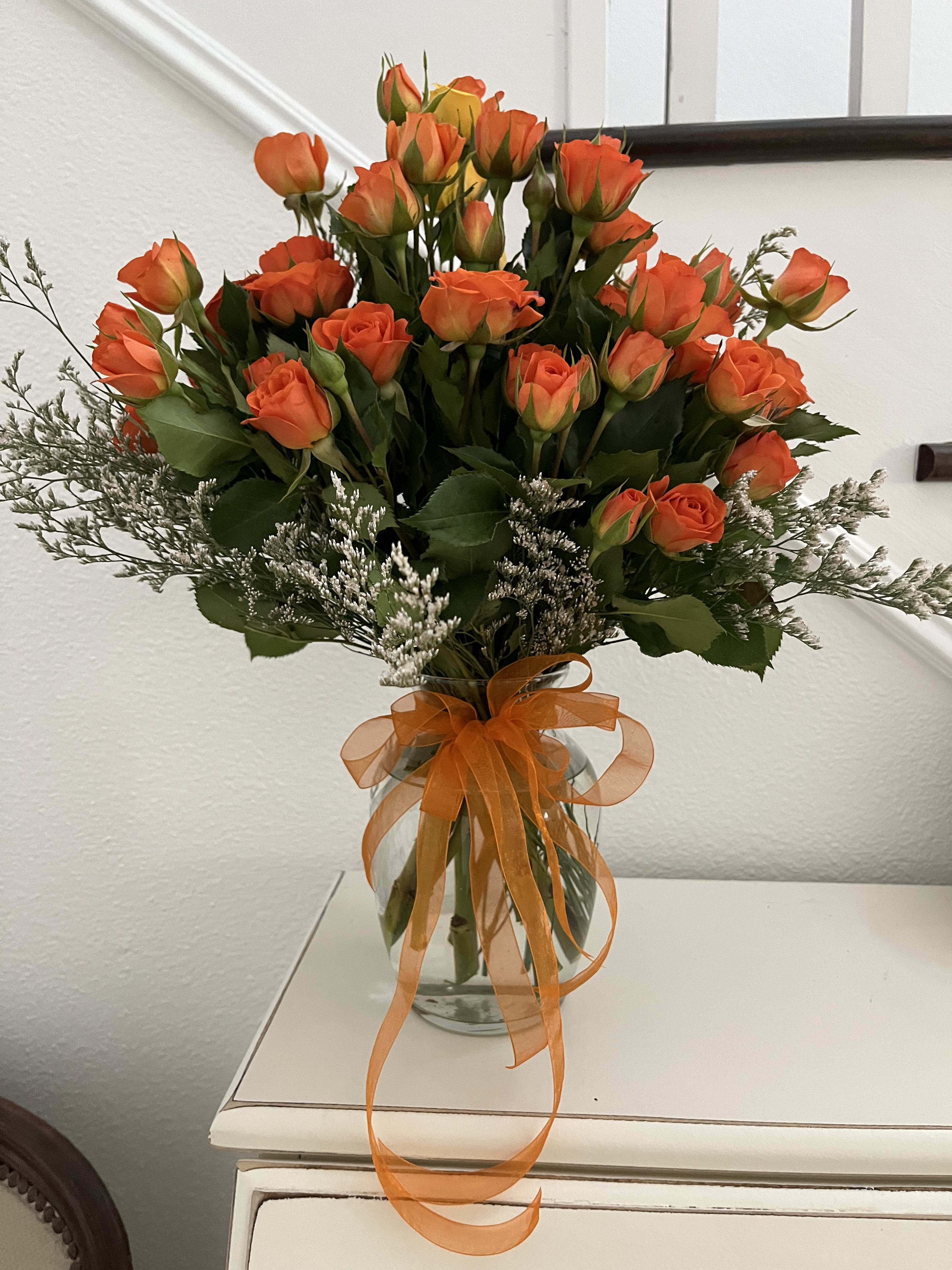 Orange roses in a glass vase with an orange ribbon