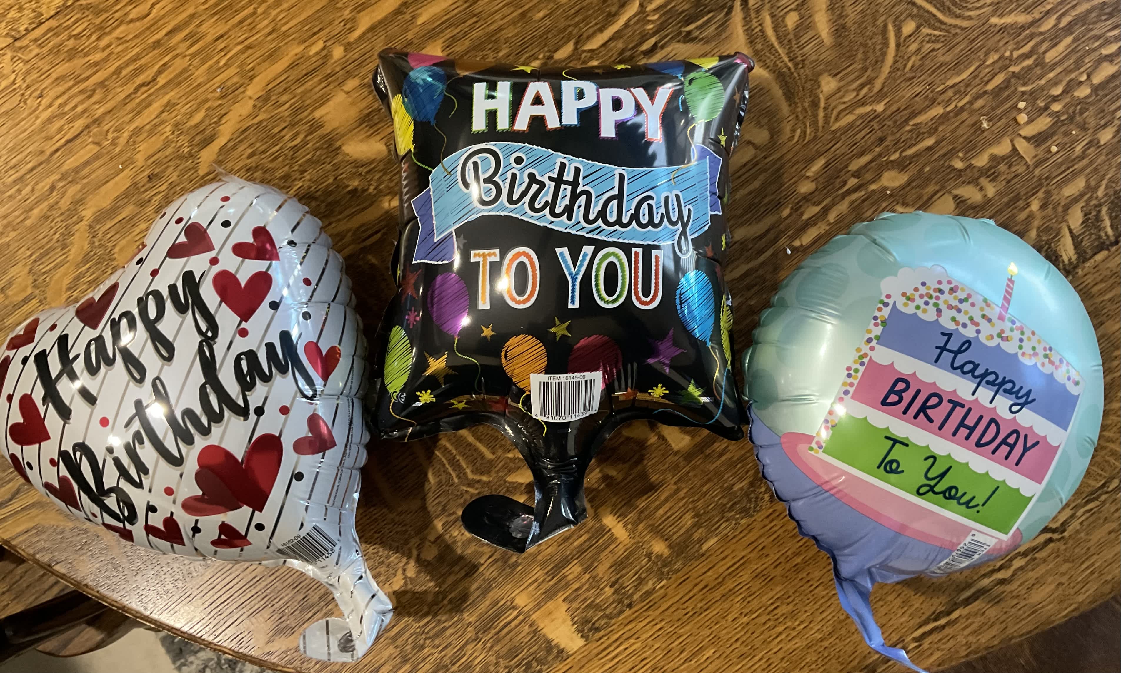 Three birthday foil balloons on a wooden table
