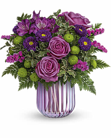 Purple roses and mixed purple flowers in a pink glass vase