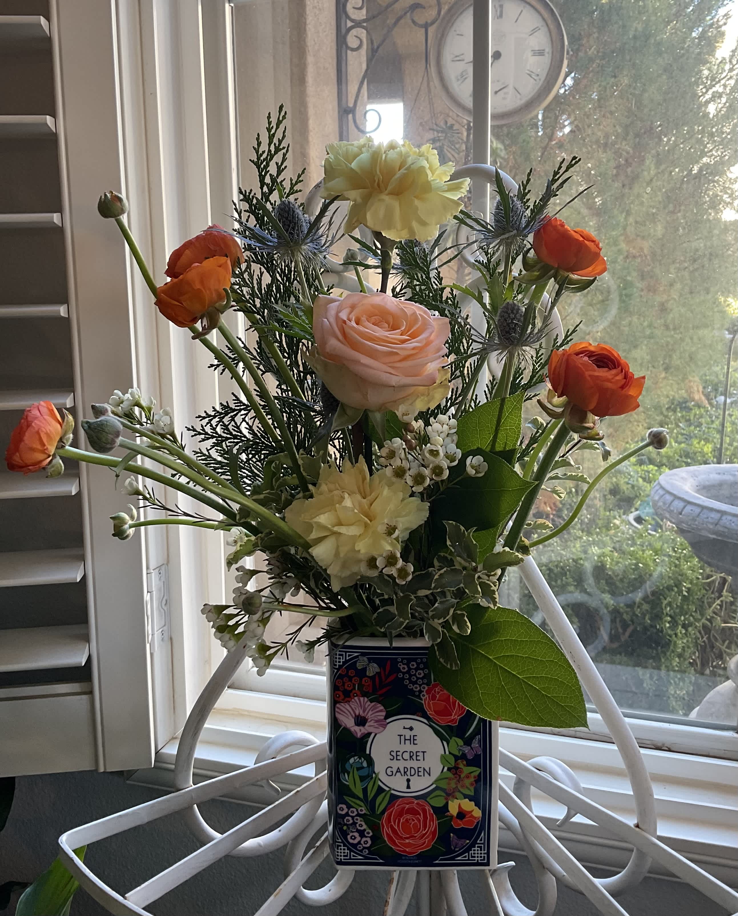 Mixed bouquet of roses, ranunculus, and blue thistle in a decorative box