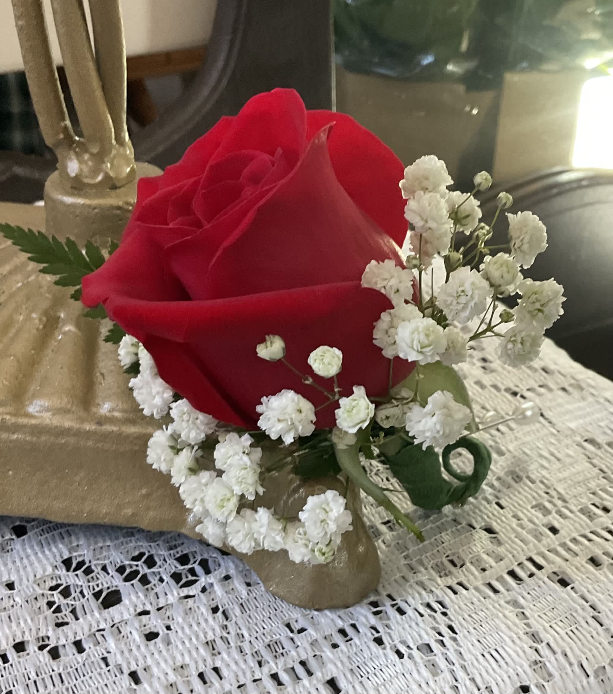 Single red rose with white baby's breath in a gold holder