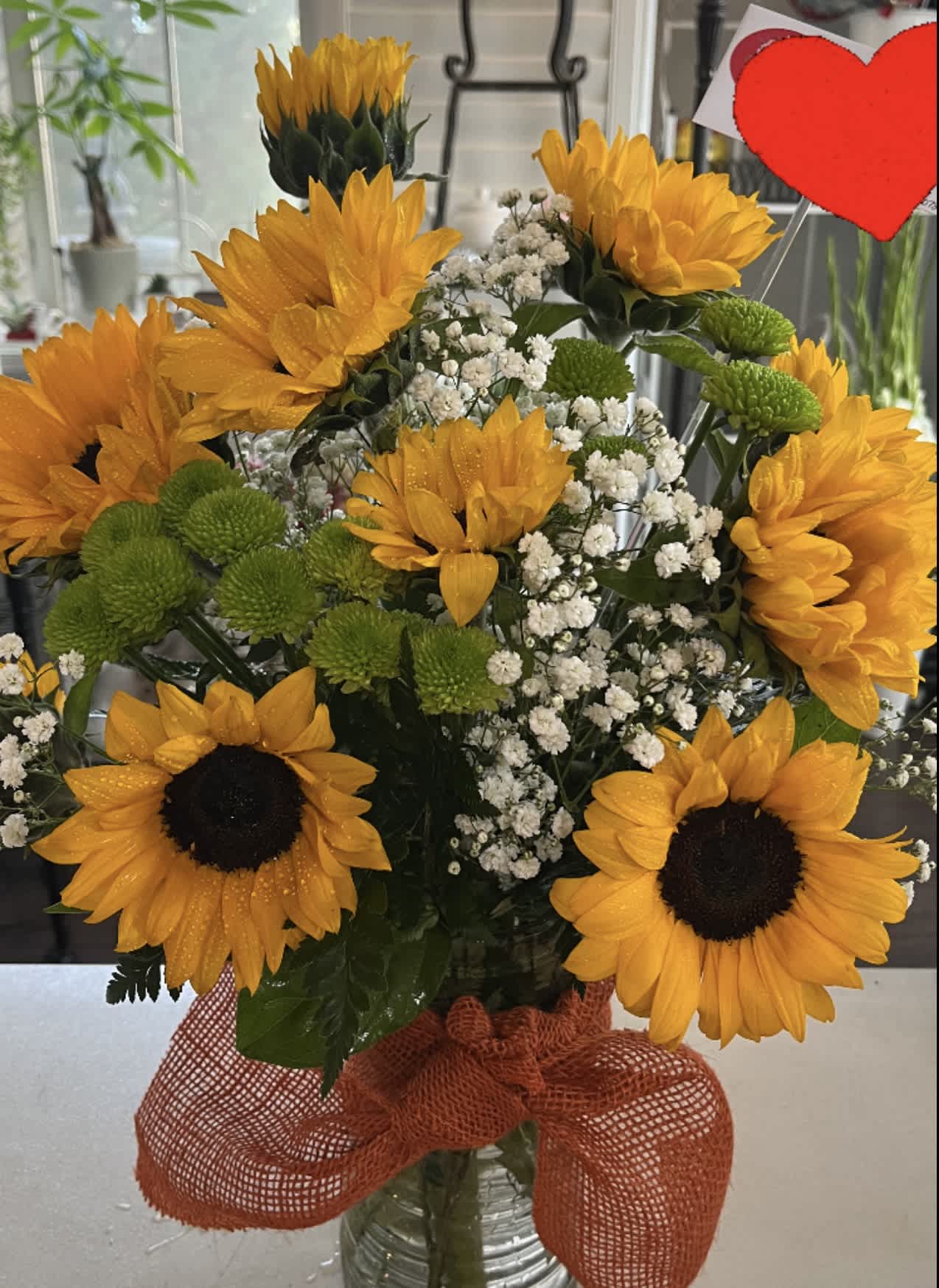 Bouquet of sunflowers, green button mums, and baby's breath in a glass vase