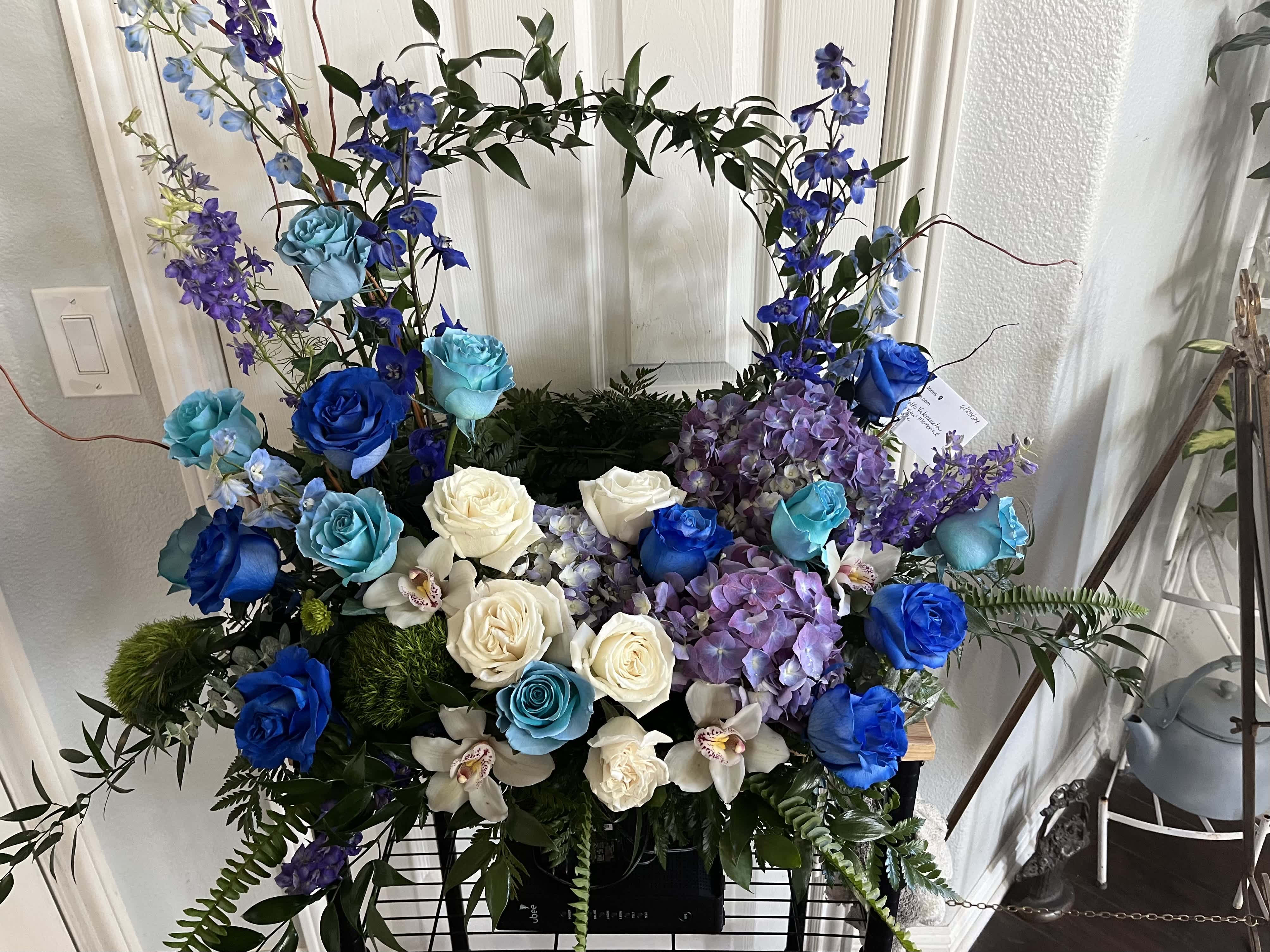 Blue, white, and purple floral arrangement with roses and orchids
