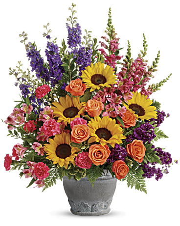 Colorful bouquet of sunflowers, roses, and purple flowers in a gray vase