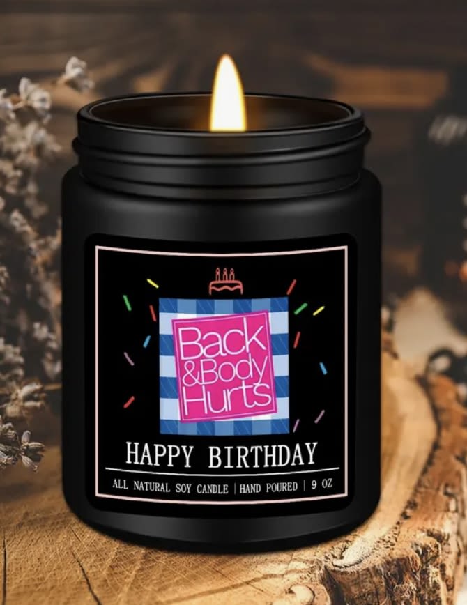 Black jar candle with a lit flame and birthday label