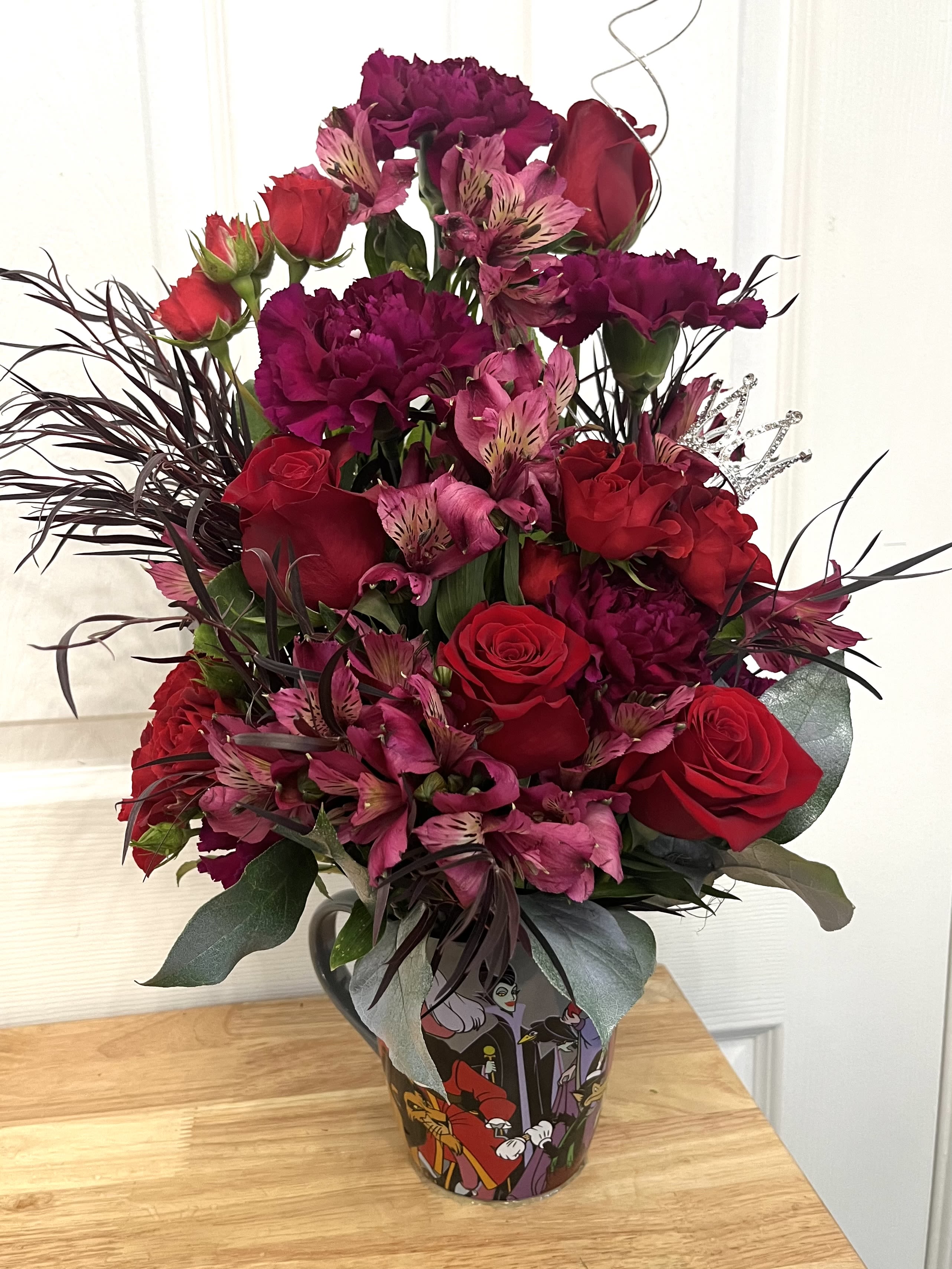 Bouquet of red roses, pink alstroemeria, and dark carnations in a decorative vase