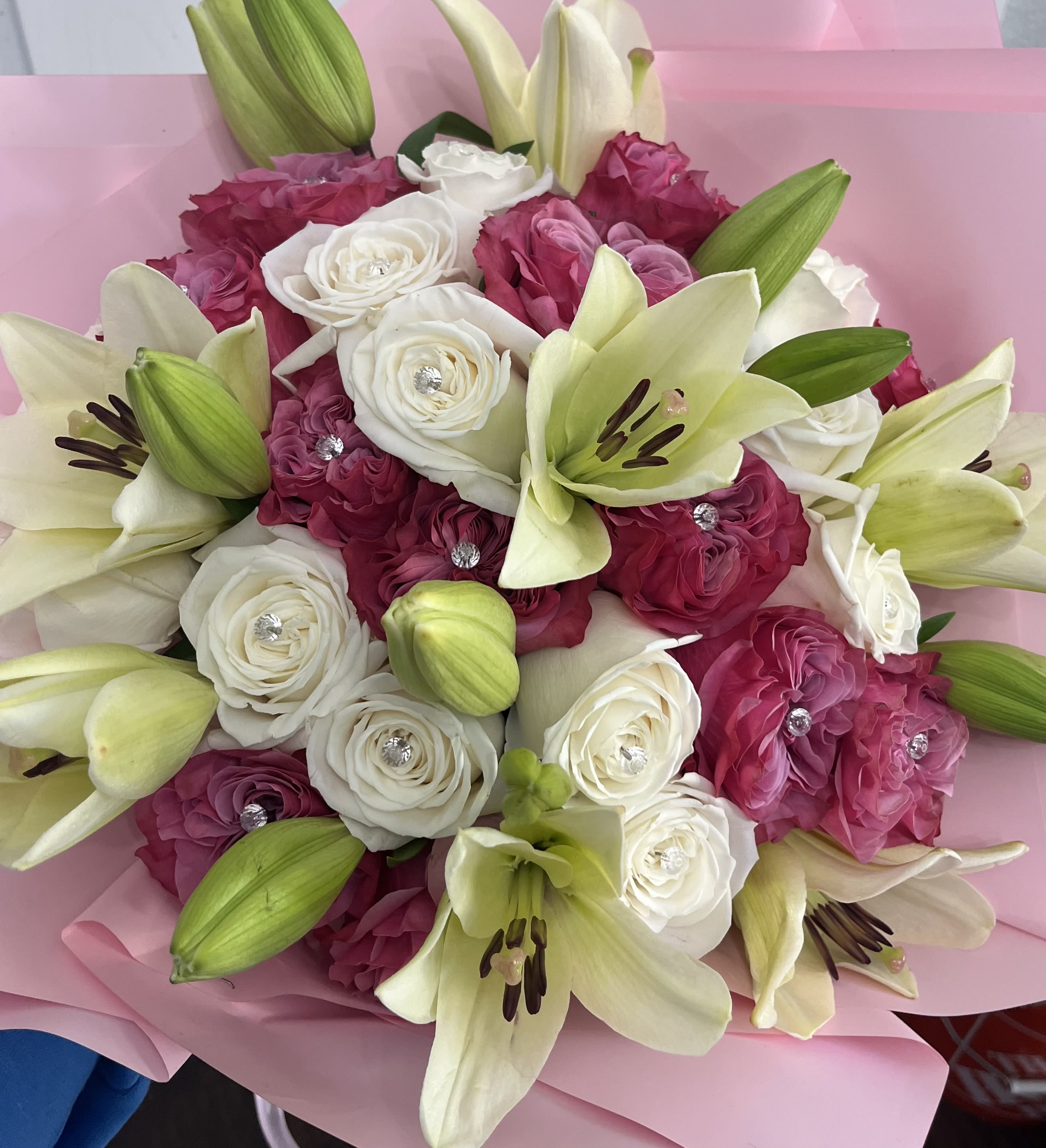 Pink and white bouquet with lilies and roses wrapped in pink paper