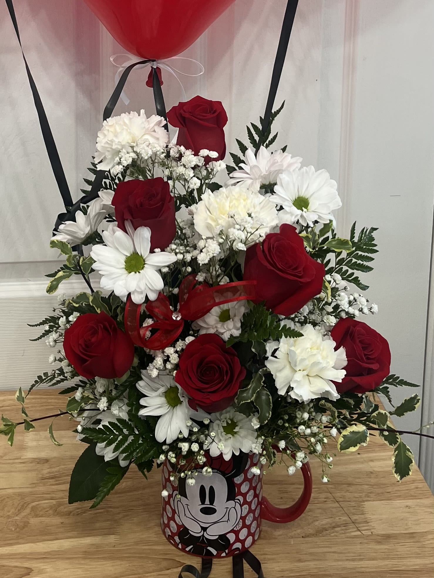 Red roses and white daisies arranged in a Mickey Mouse mug with a red balloon