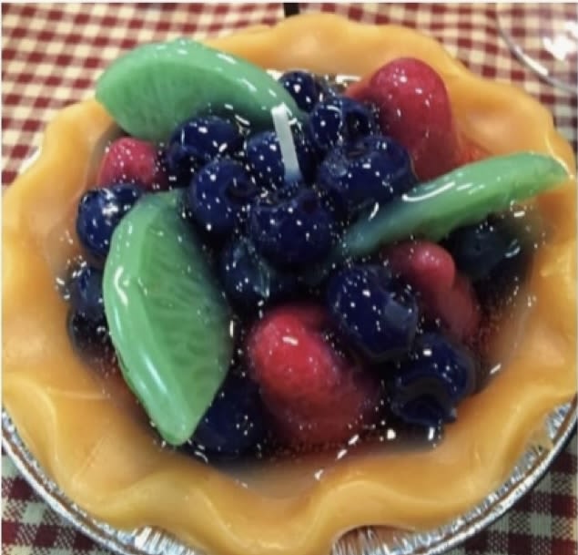 A fruit tart topped with blueberries, strawberries, and green fruit slices