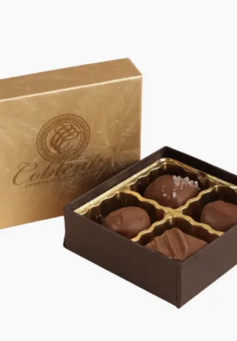 Box of assorted chocolates with a gold lid and brown tray
