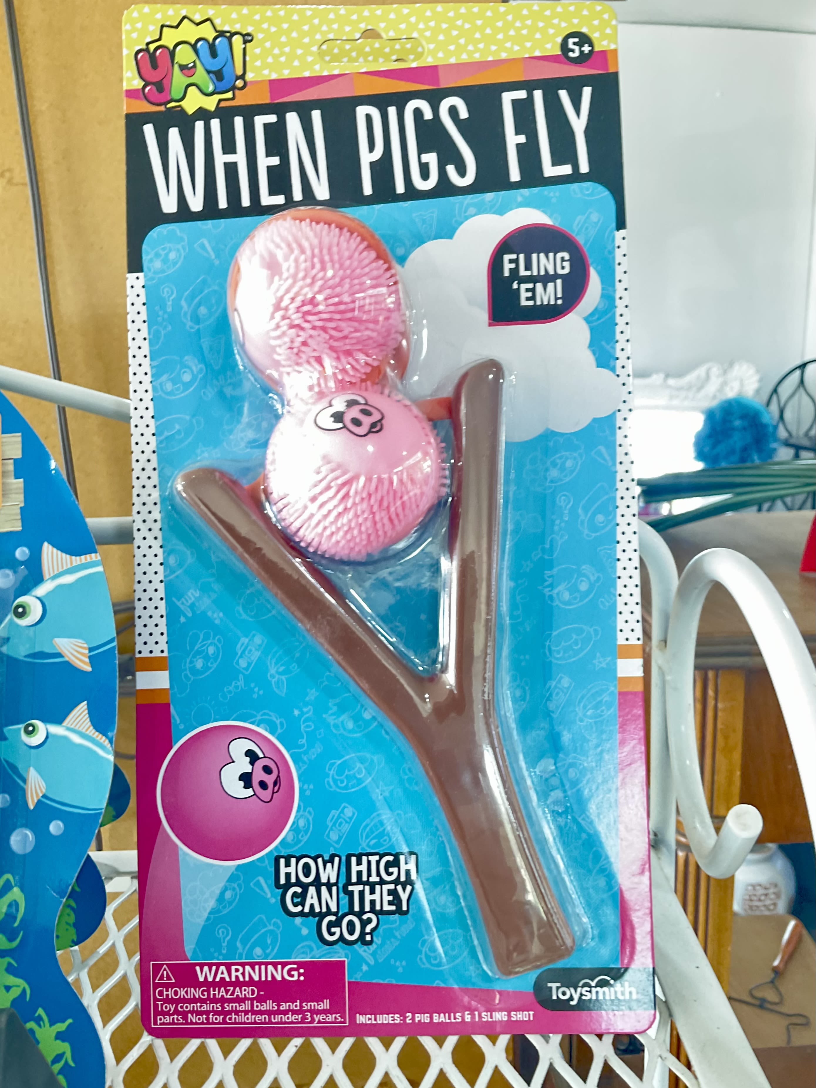 Packaged pig-themed toy slingshot with two pink pig balls