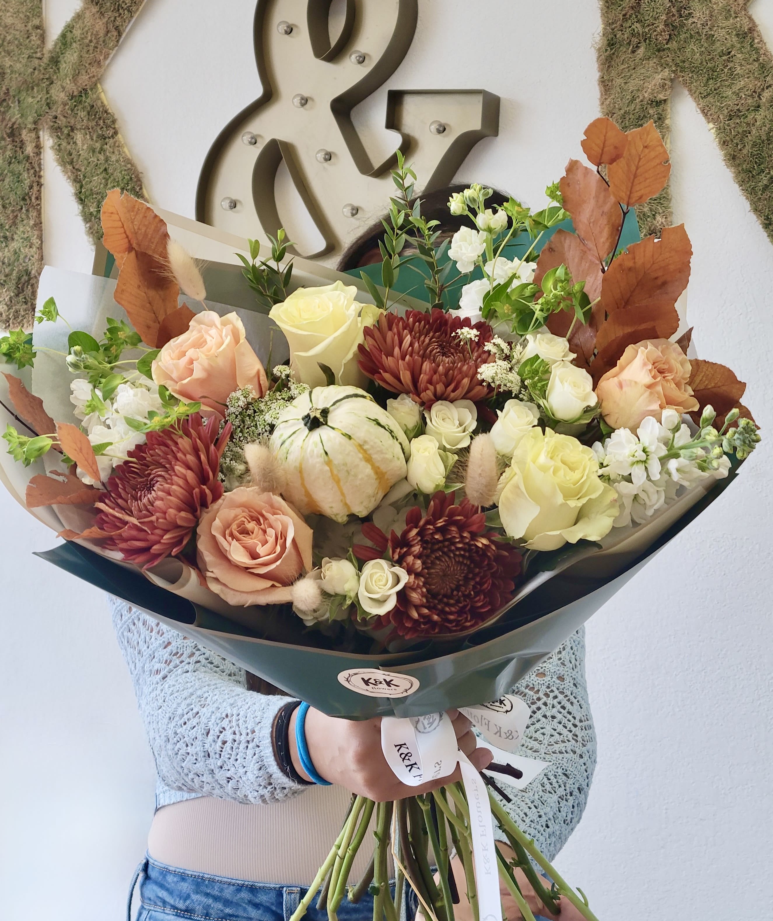 Handheld bouquet with roses, chrysanthemums, and a small pumpkin centerpiece