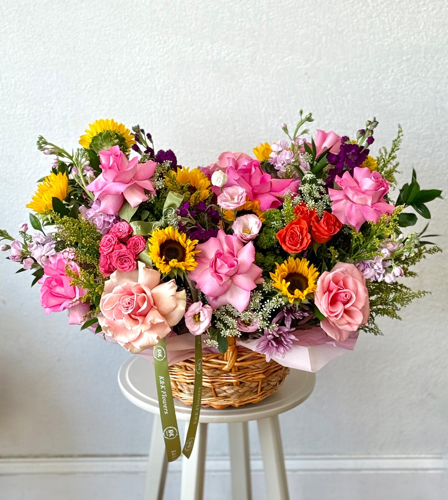 Mixed bouquet in a wicker basket with pink roses and sunflowers