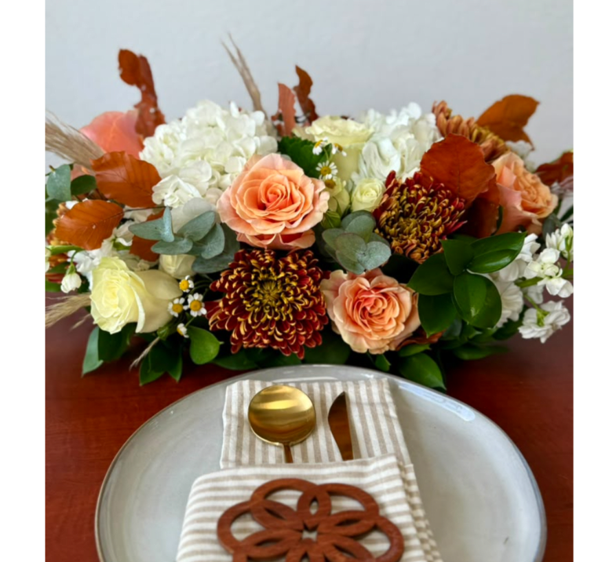 Peach and white floral arrangement with autumn leaves on a table setting