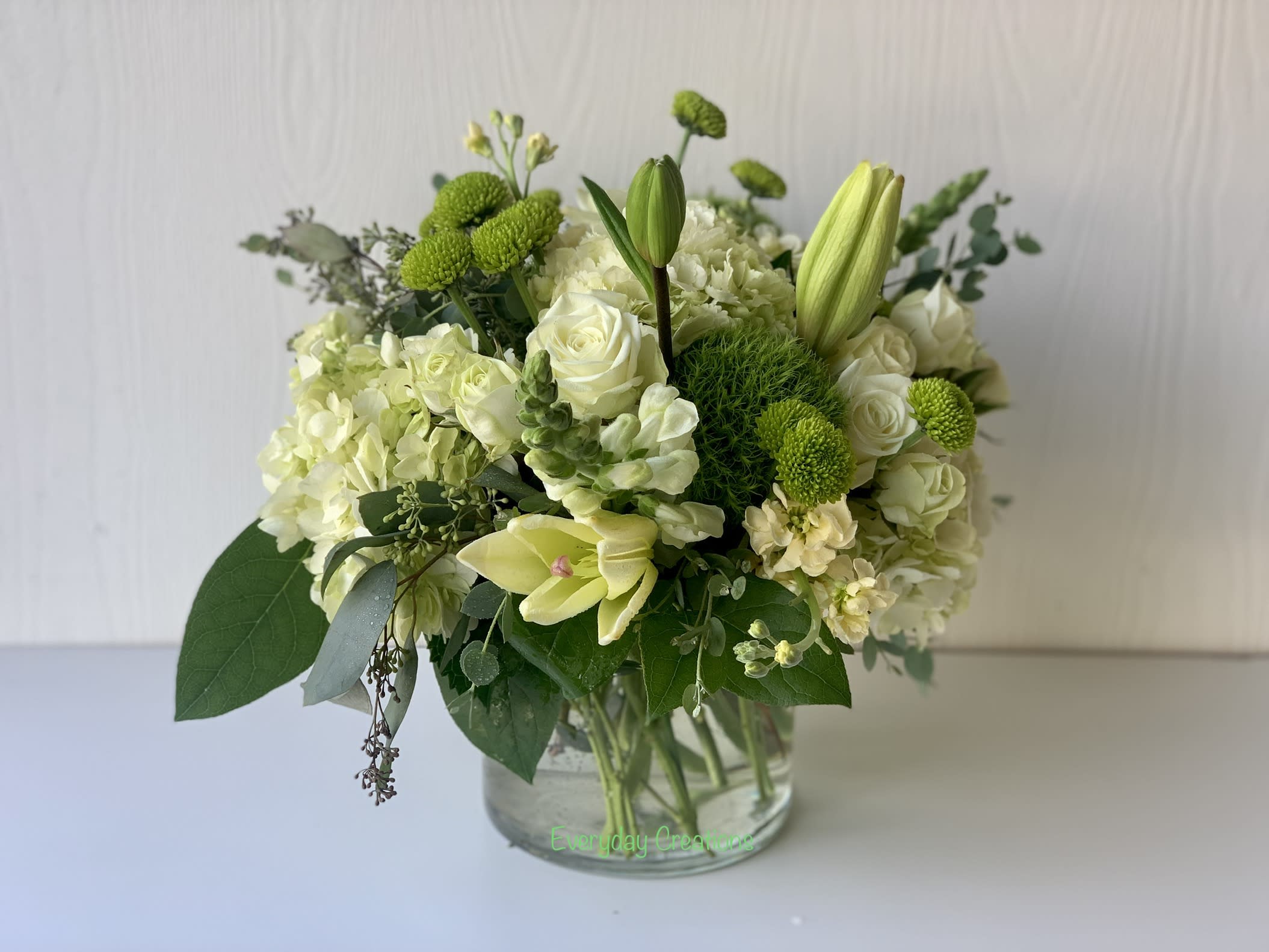 White and green floral arrangement in a clear glass vase