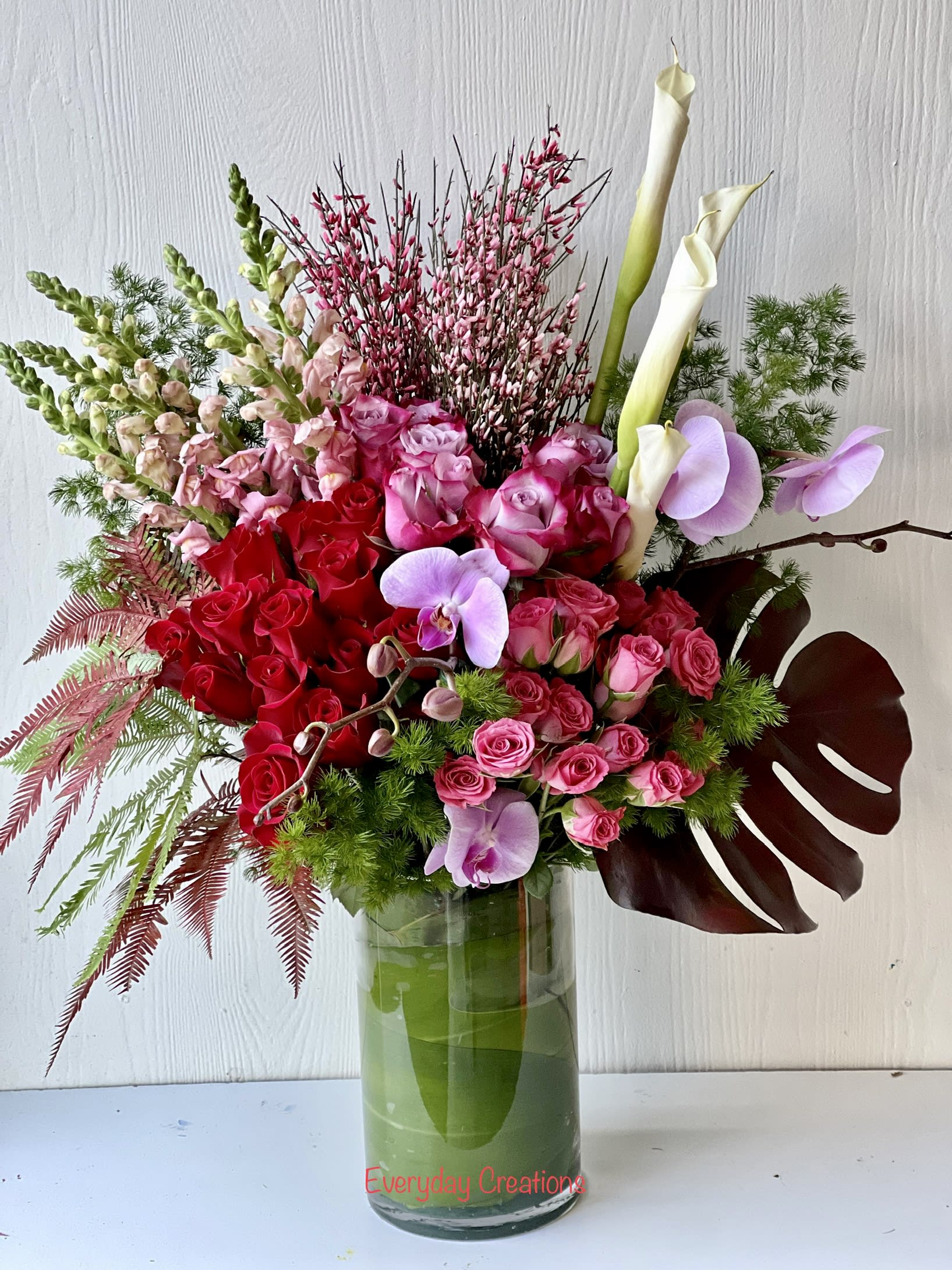 Mixed bouquet of red and pink roses with white calla lilies in a glass vase