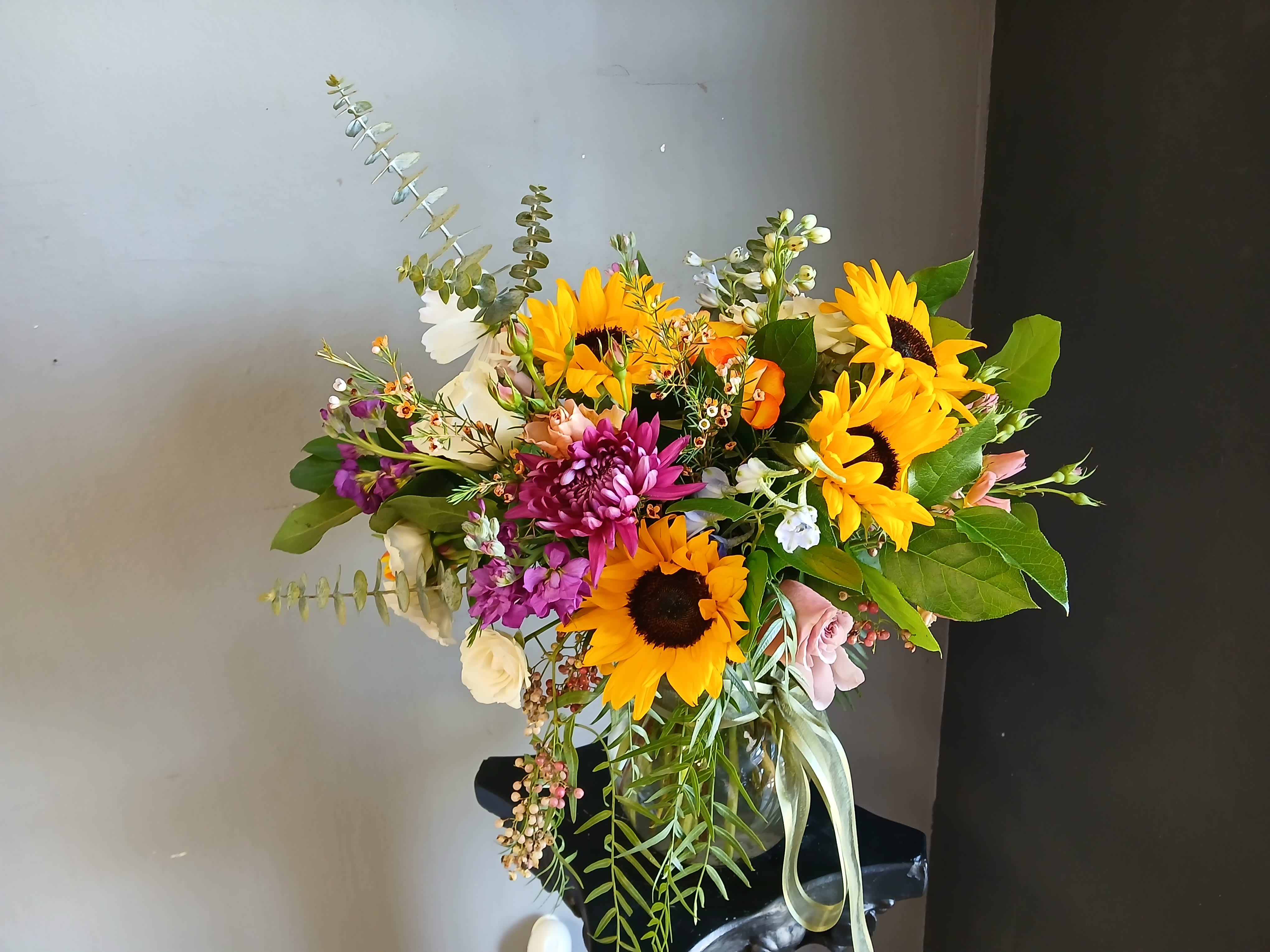 Bouquet of sunflowers, purple blooms, and mixed flowers in a black vase