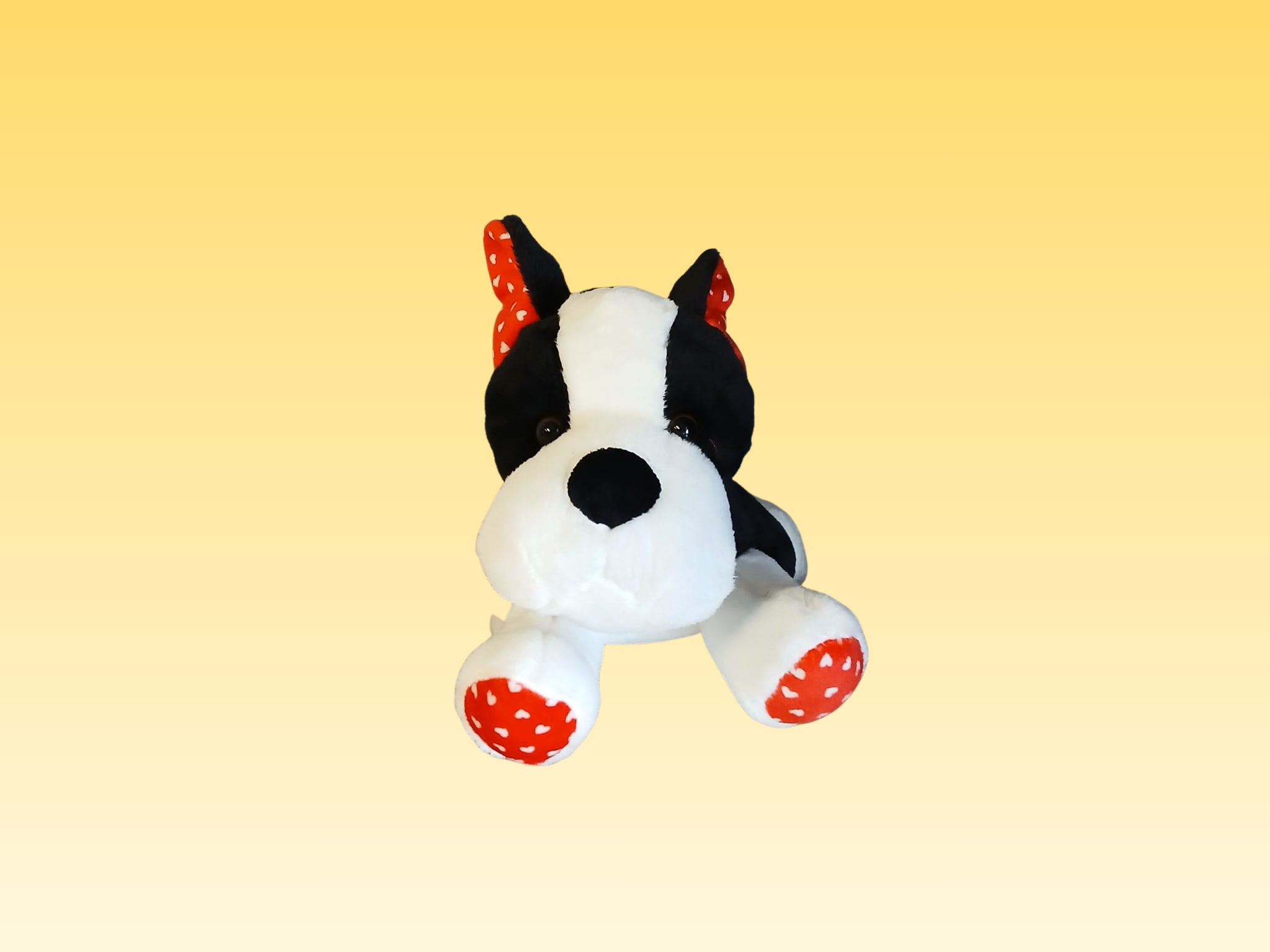 Black-and-white plush dog with red polka-dot ears and paws