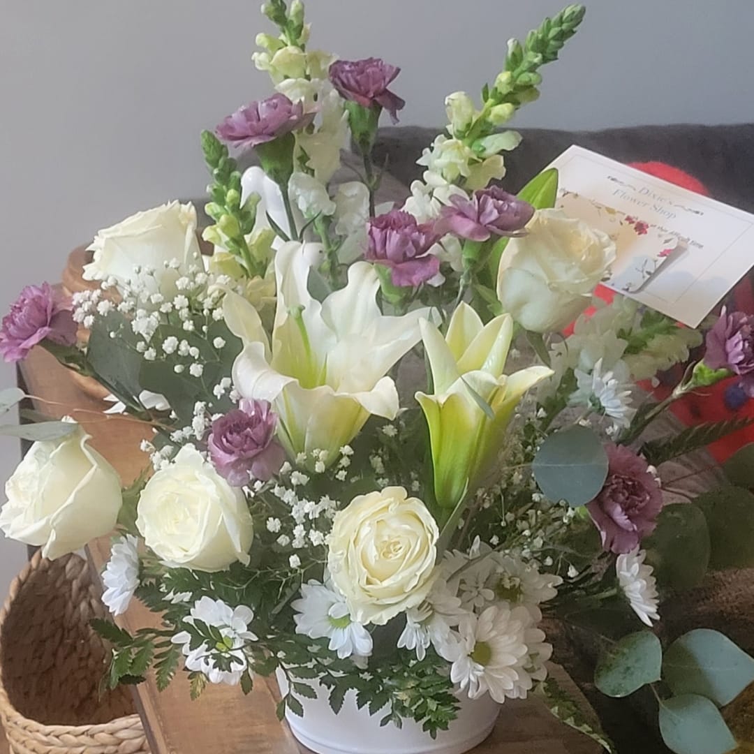 White and purple mixed flower arrangement in a white container