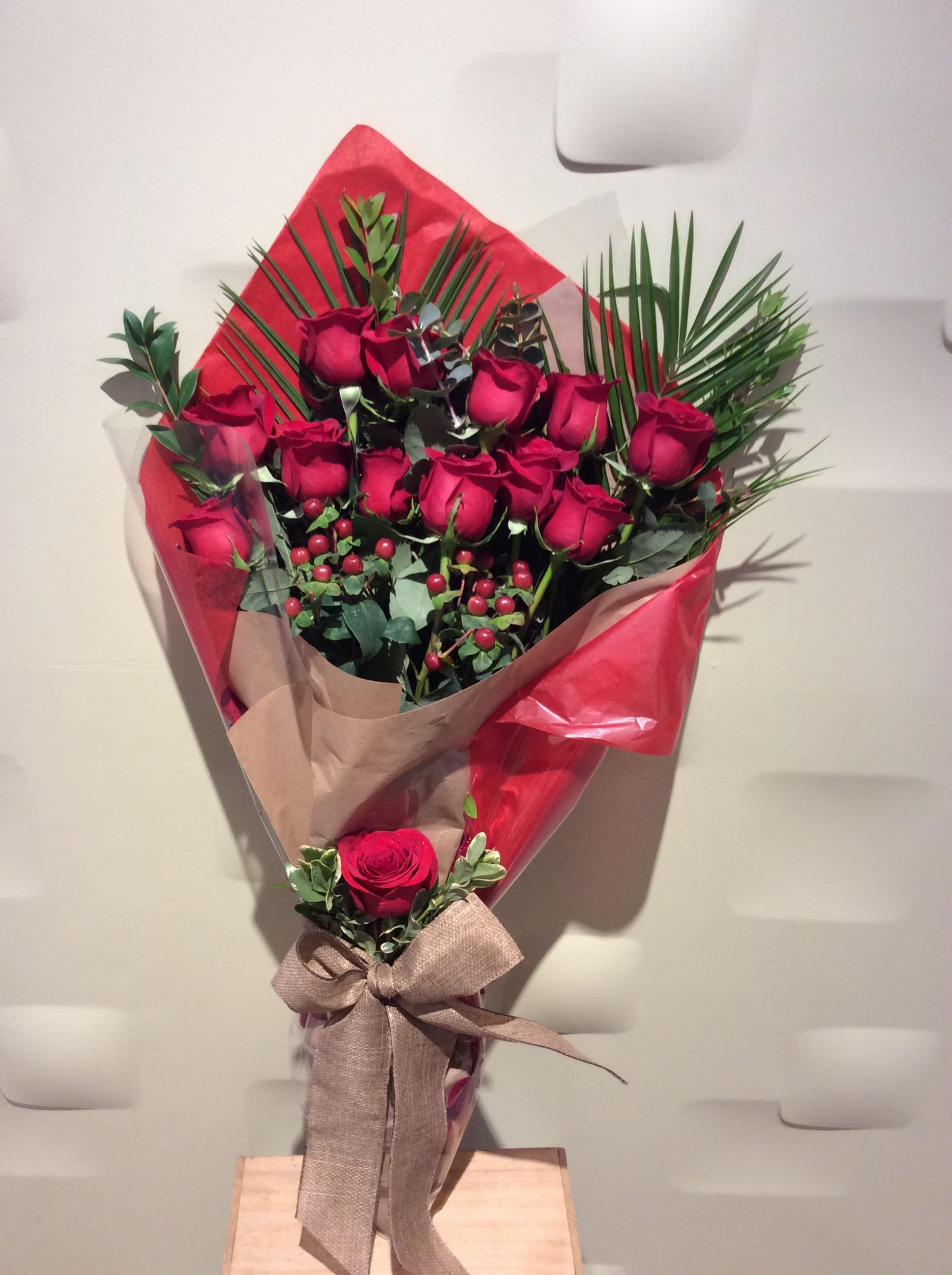 Bouquet of red roses wrapped in red and tan paper with a ribbon