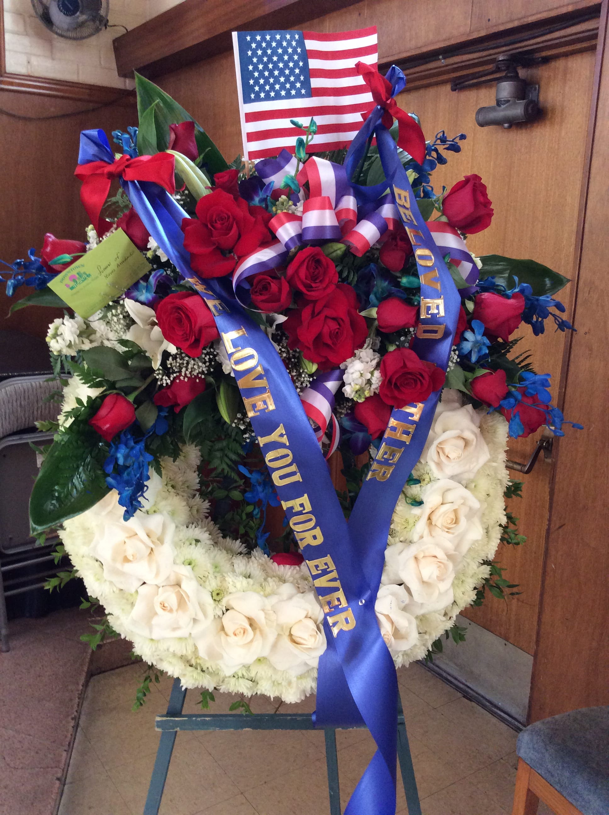 Heart-shaped floral wreath with red and white roses and patriotic ribbons