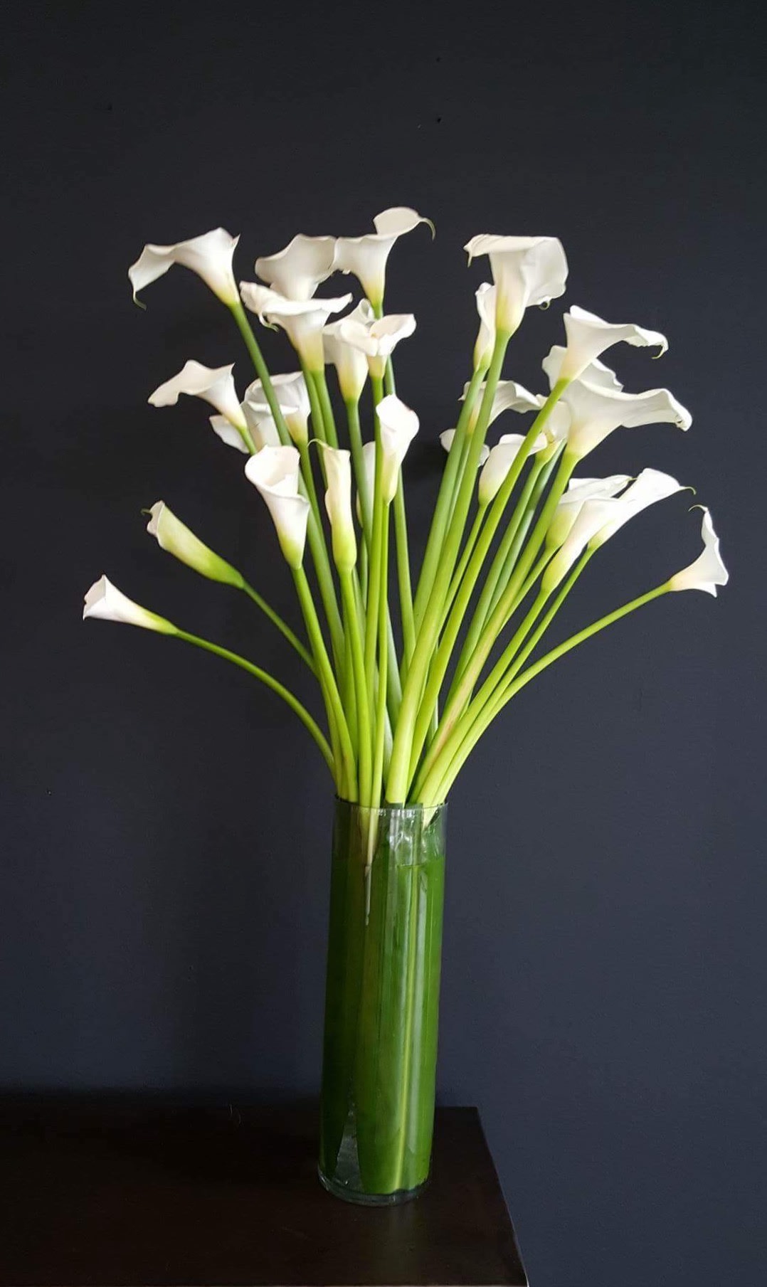 White calla lilies in a tall glass vase