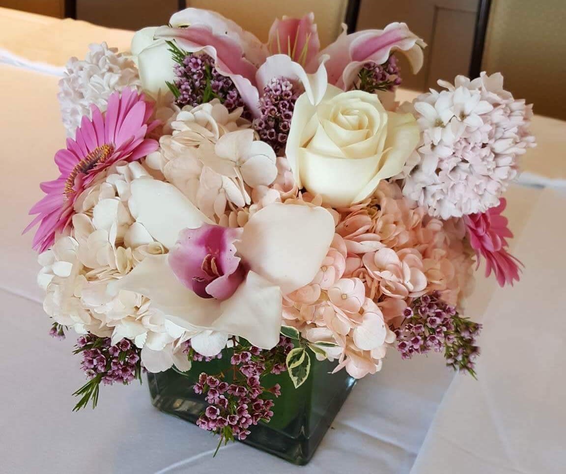 Pink and white floral arrangement in a square glass vase
