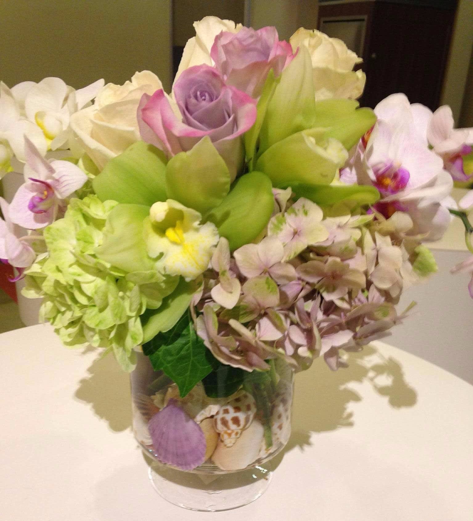 Bouquet of roses, orchids, and hydrangea in a clear glass vase