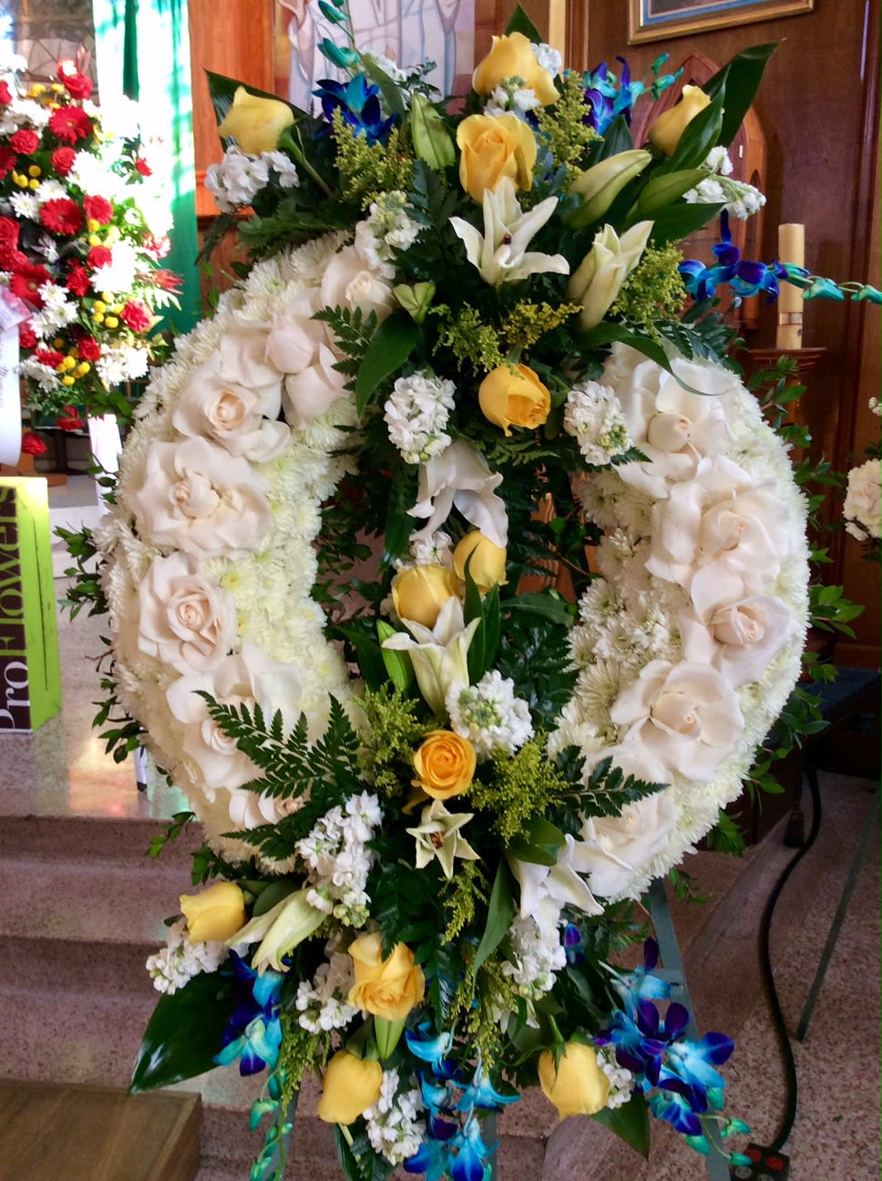 Large floral wreath with white roses, lilies, and yellow accents