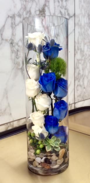 Tall glass vase with white and blue roses and small accent flowers