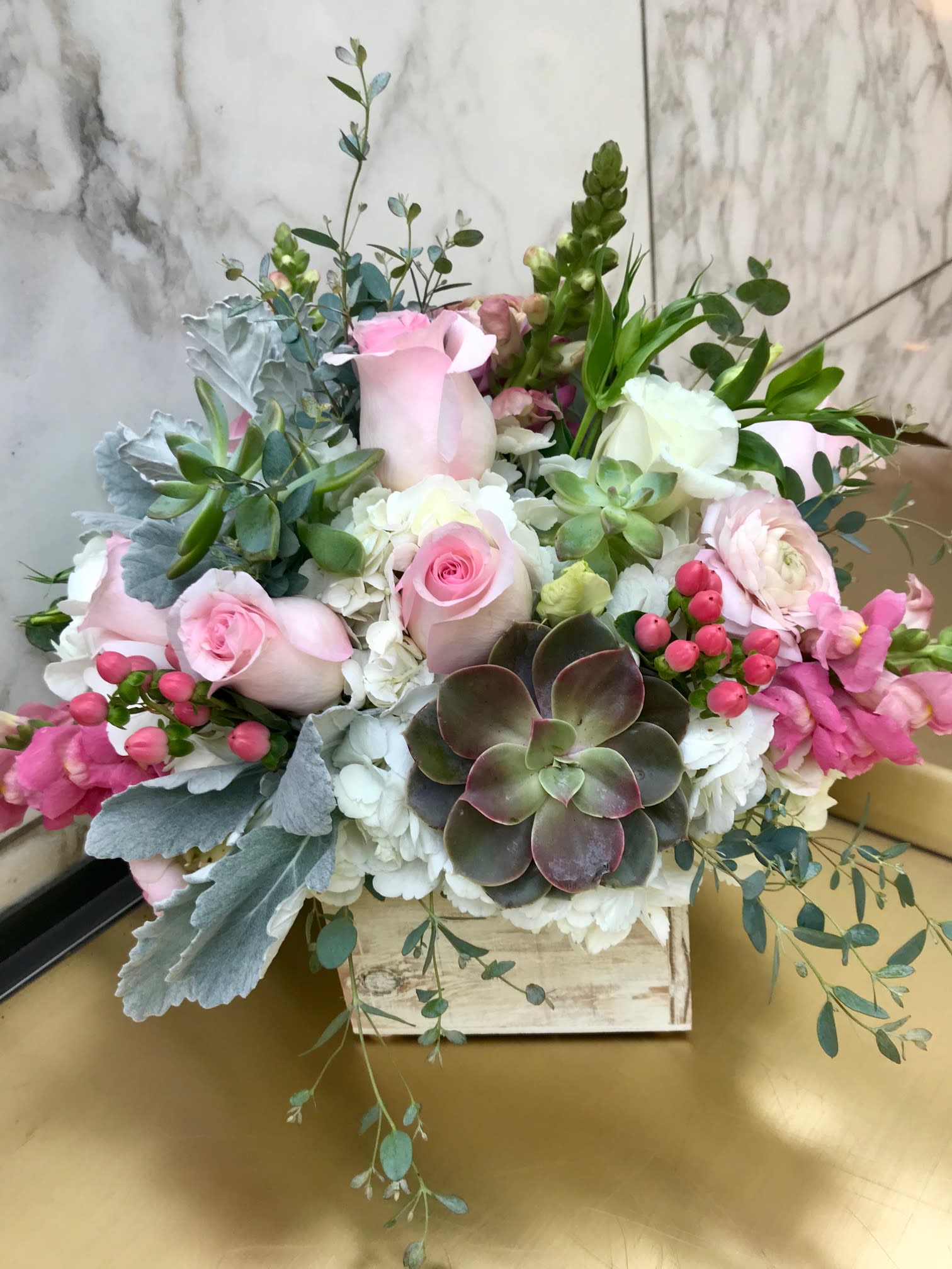 Pink roses and white blooms arranged with succulents in a wooden box