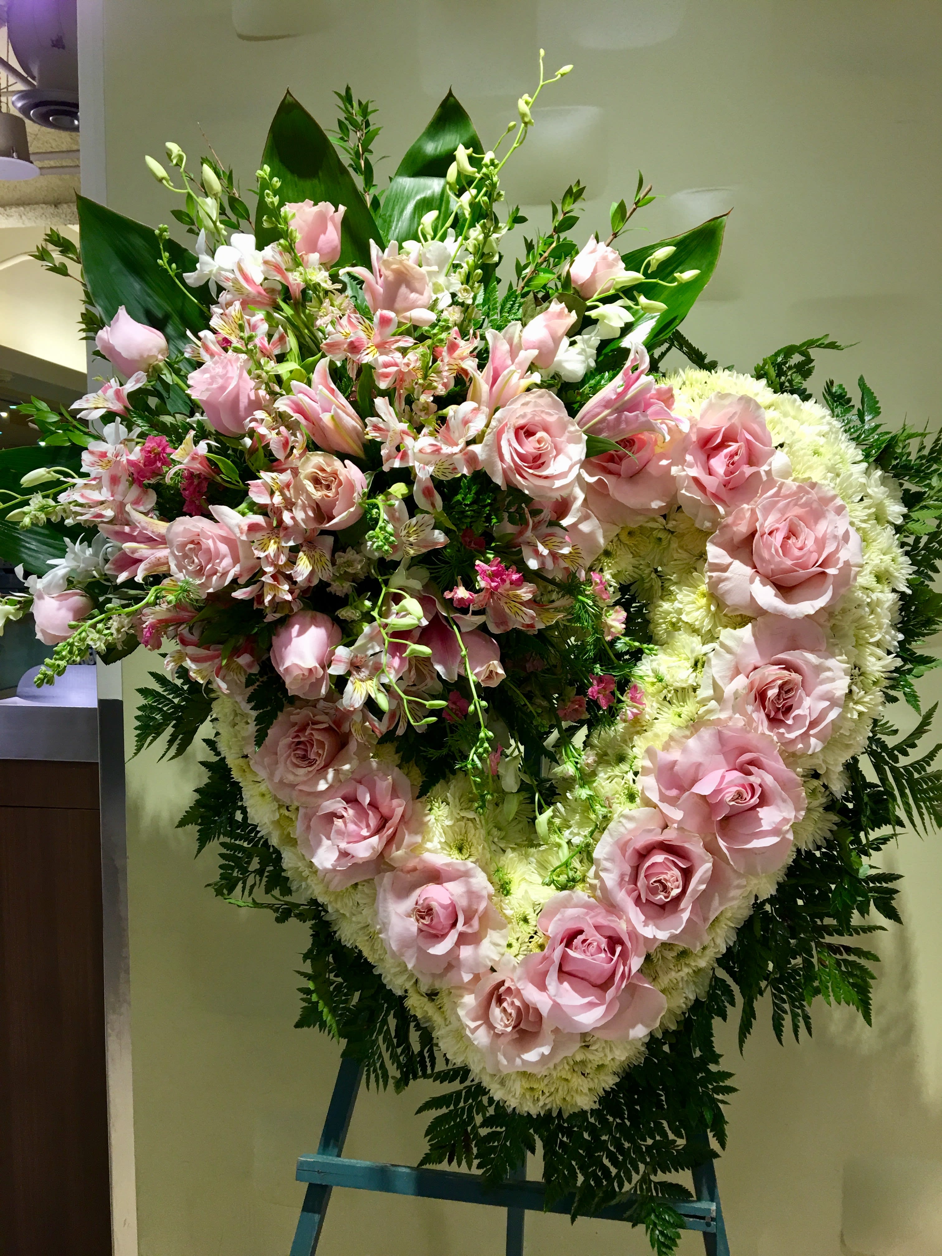 Large pink rose and lily funeral spray on an easel
