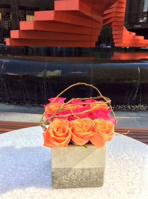 Basket of orange and pink roses with a twig handle