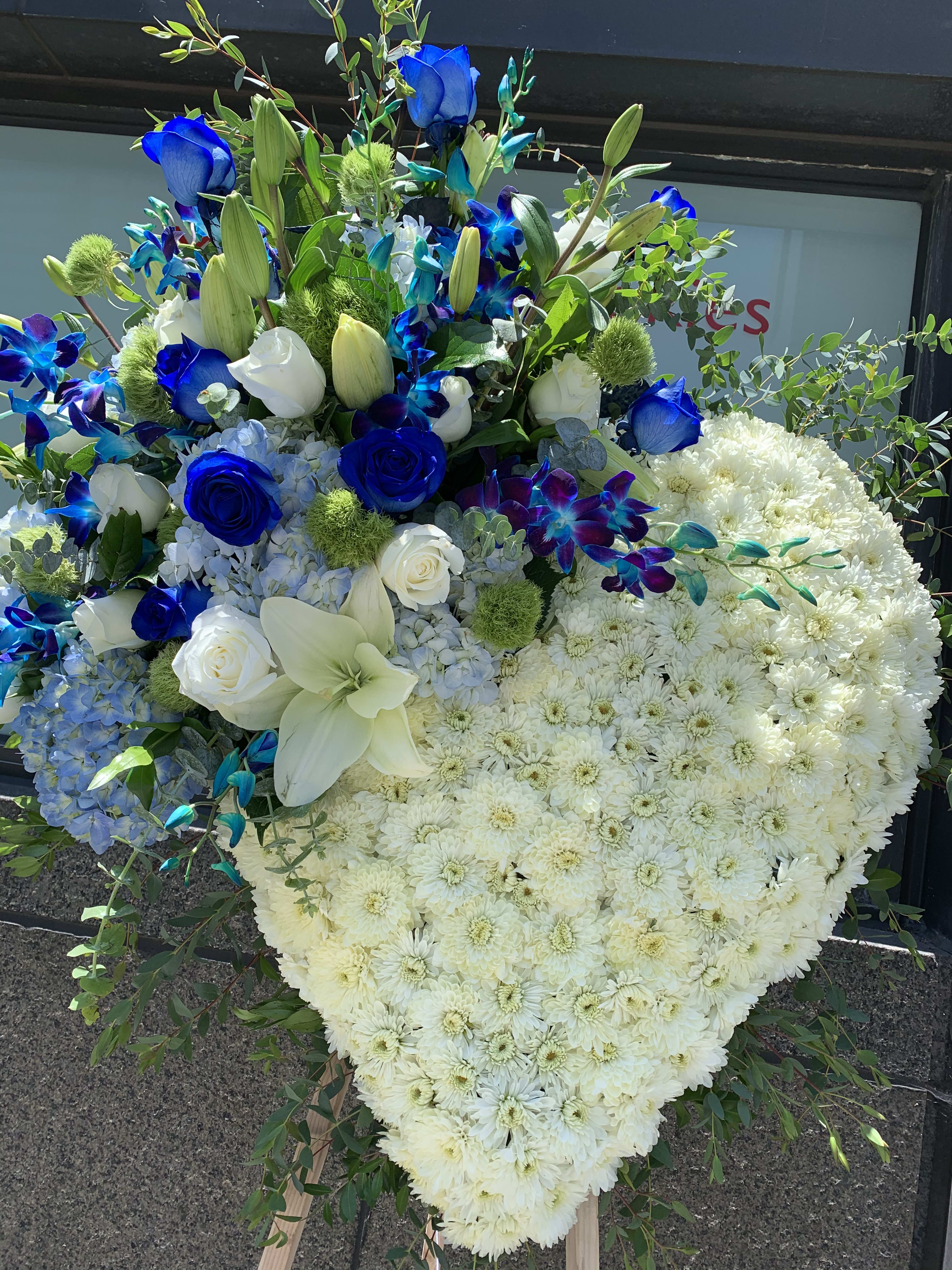 Heart-shaped floral tribute with white chrysanthemums and blue flowers