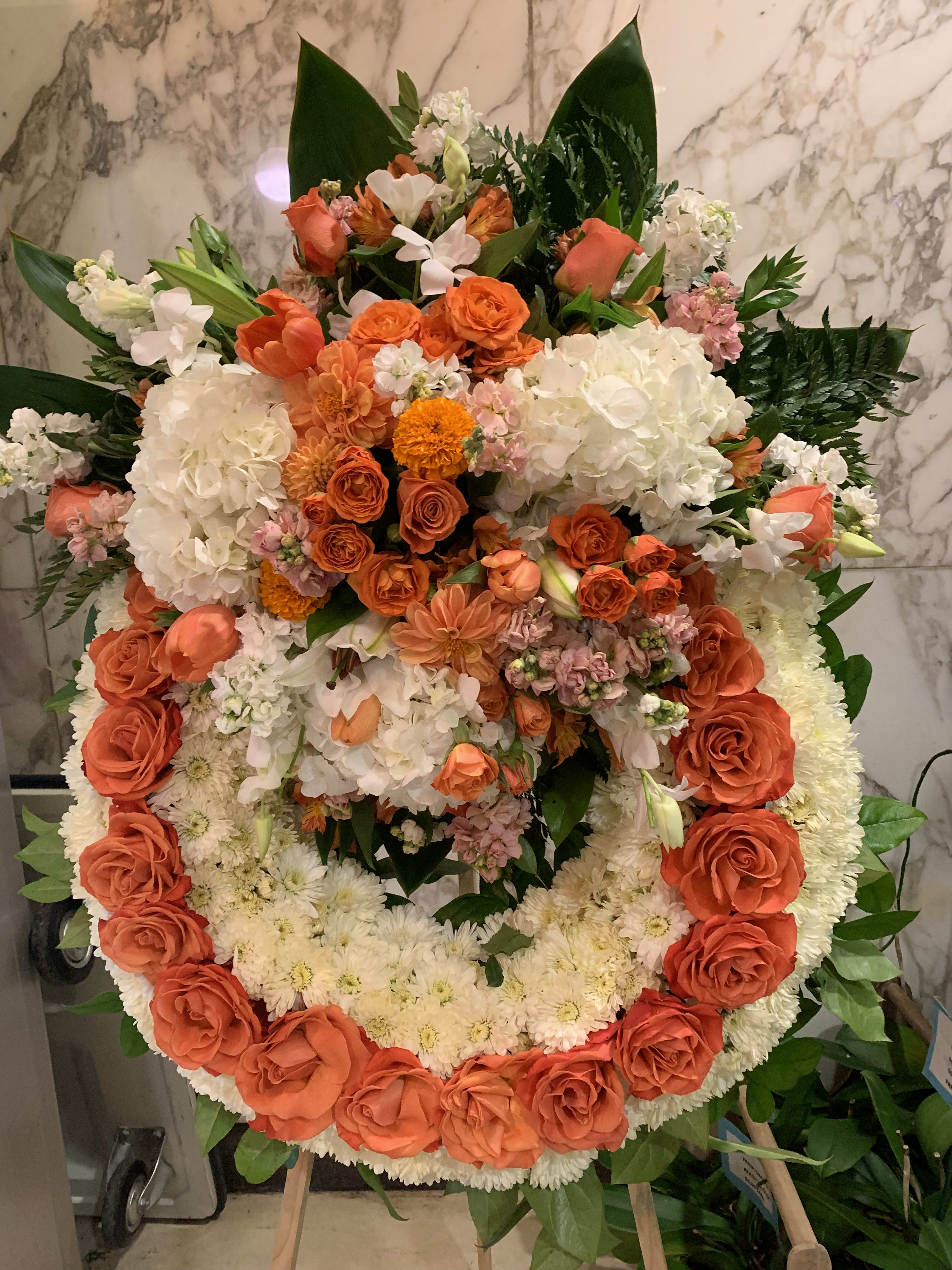 Large circular floral wreath with orange and white flowers on an easel