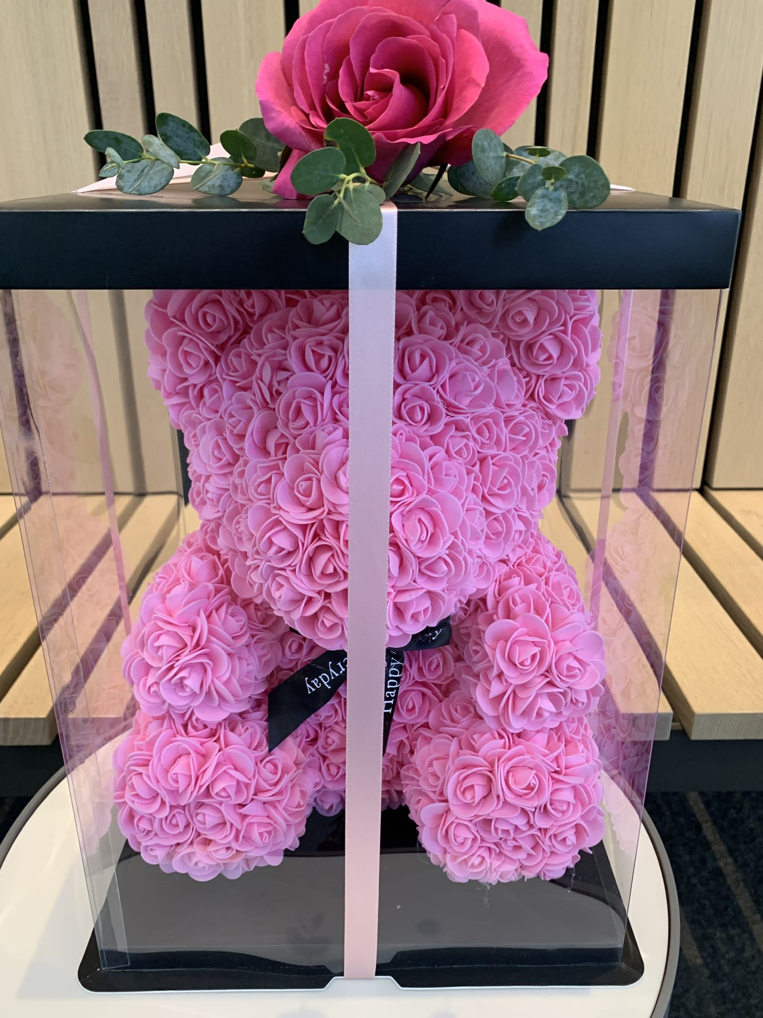 Pink rose teddy bear in a clear gift box with a ribbon